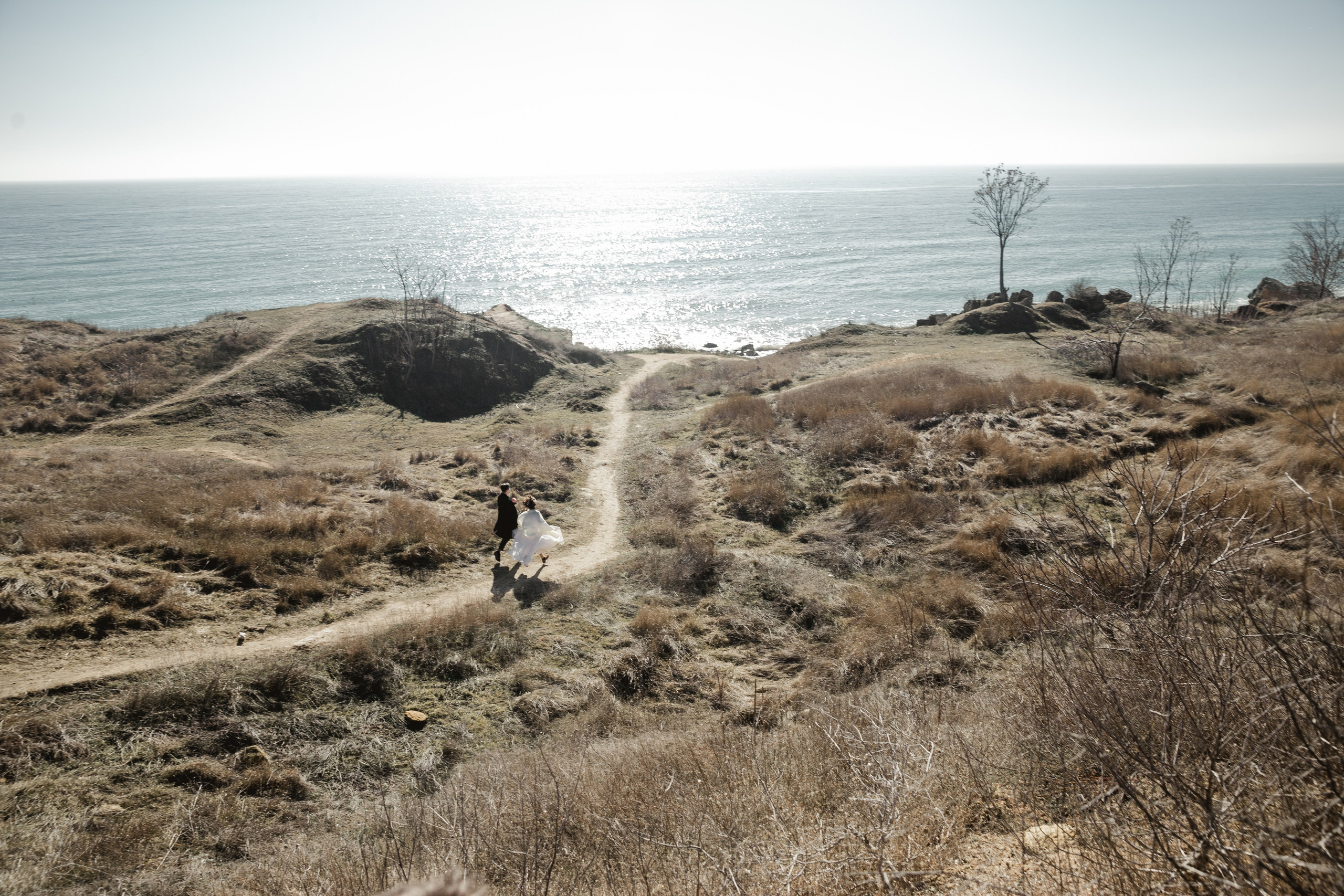 Bride and groom walking barefoot on the sand, wedding photographer Spain