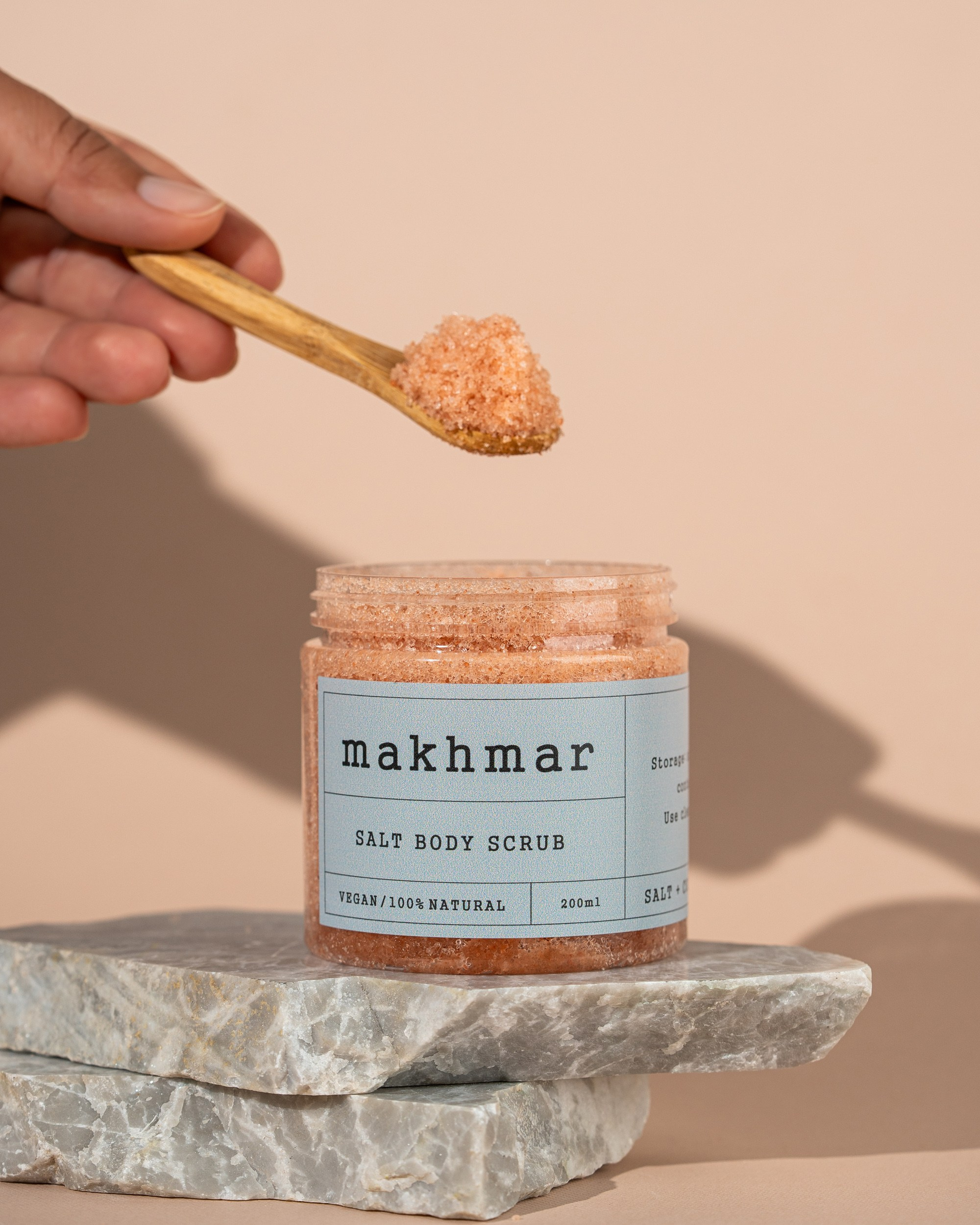 Makhmar Salt Body Scrub taxta qaşıqda təqdim olunmuş, mərmər daş üzərində və bej fonda məhsul fotoşəkili.
