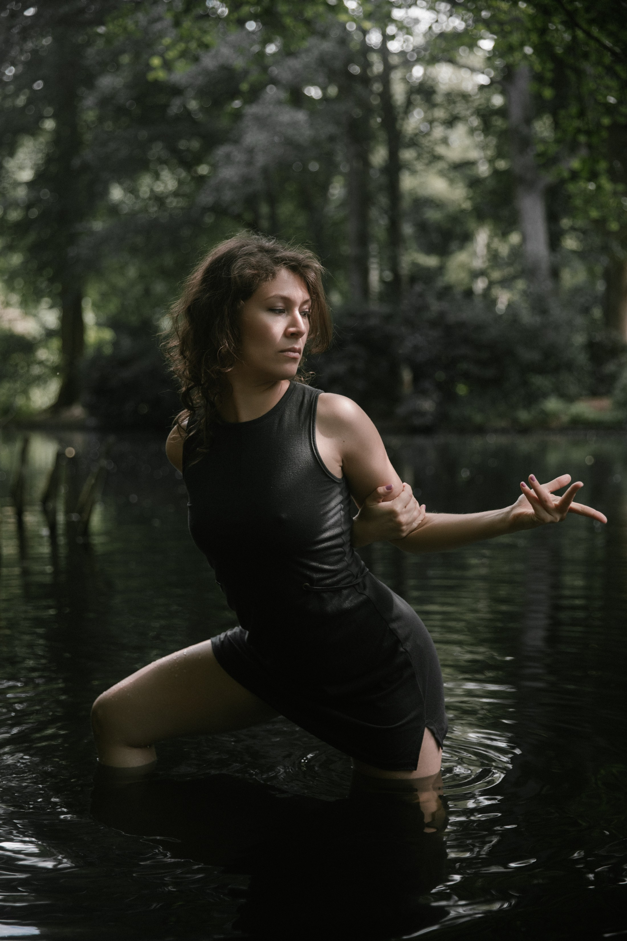Porträt einer Tänzerin mit Armbewegung im dunklen Wasser