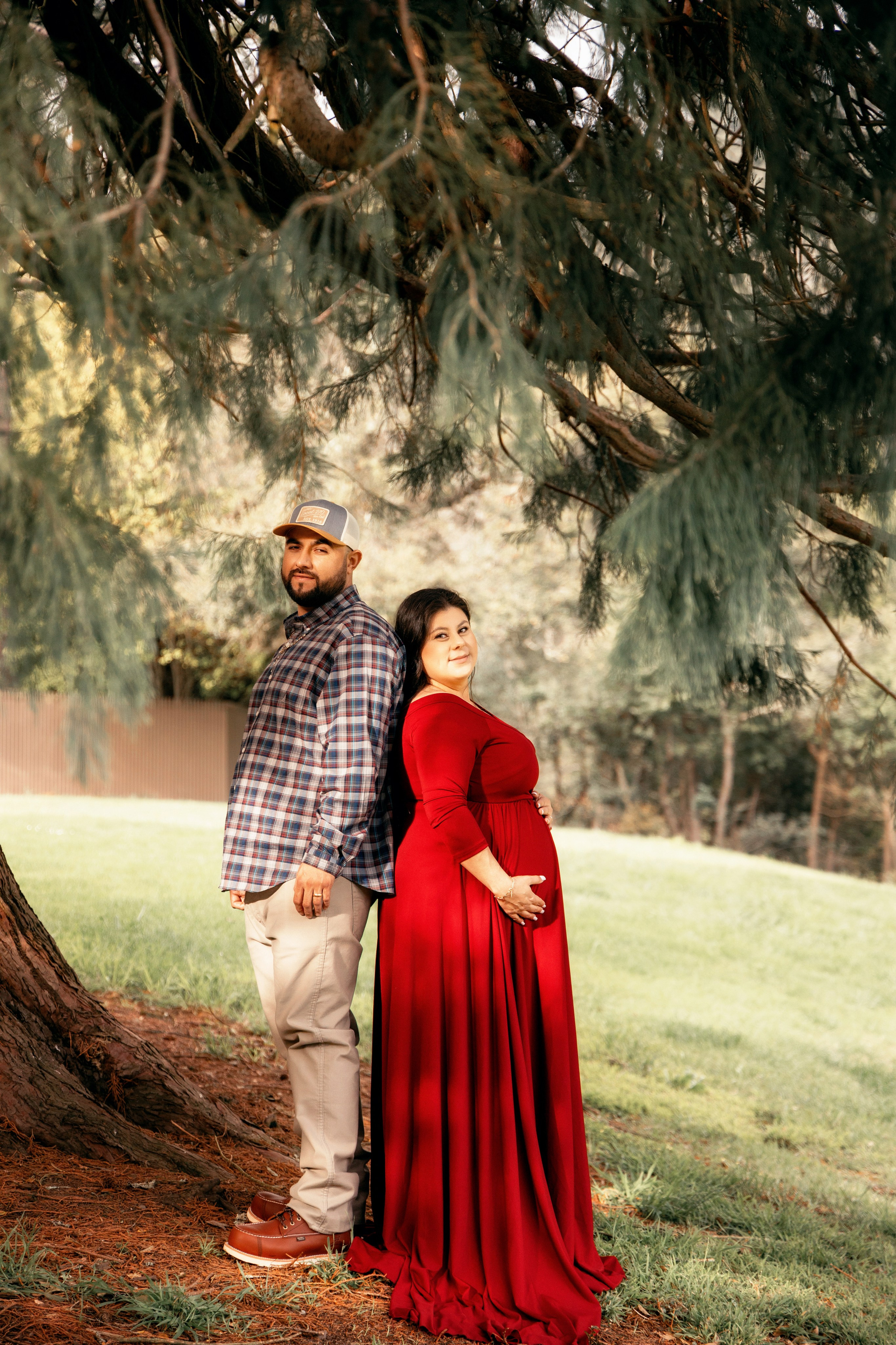 Expectant mother smiling while standing on a bridge in the forest