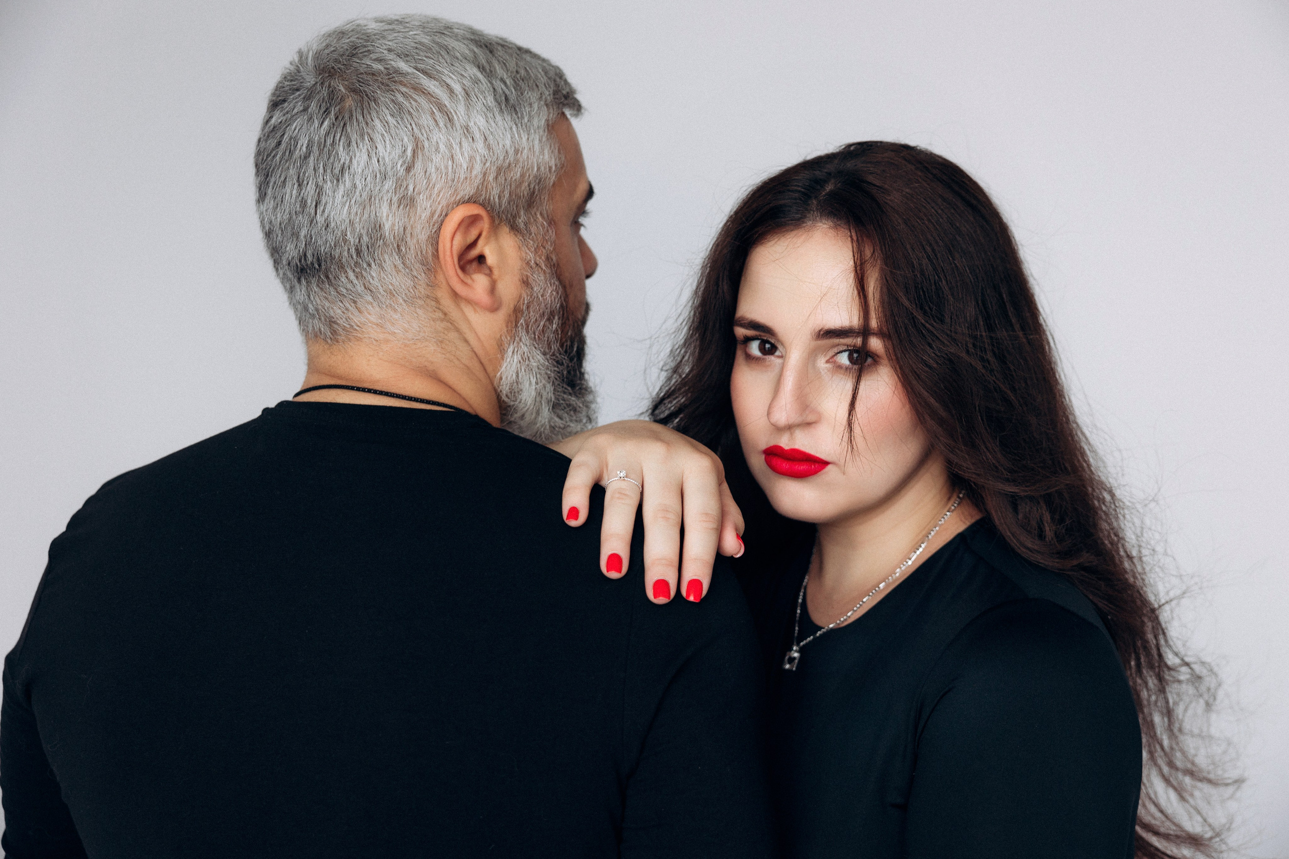 Stylowa sesja ciążowa – para w czarnych stylizacjach na jasnym tle, nowoczesna i elegancka forma.