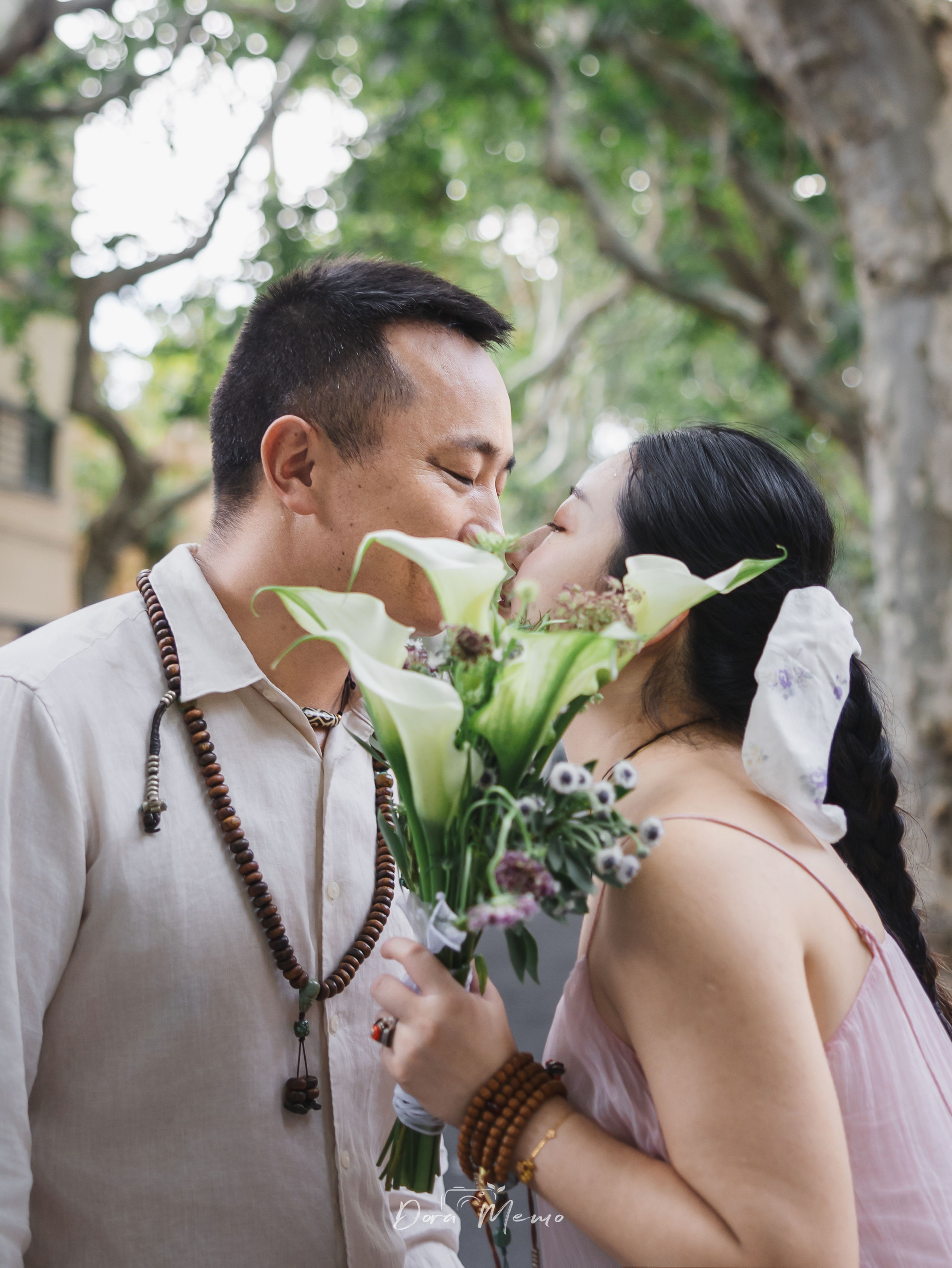Close-up of an expecting couple kissing behind a bouquet of flowers, photographed by a Shanghai family photographer in a lifestyle pregnancy session.