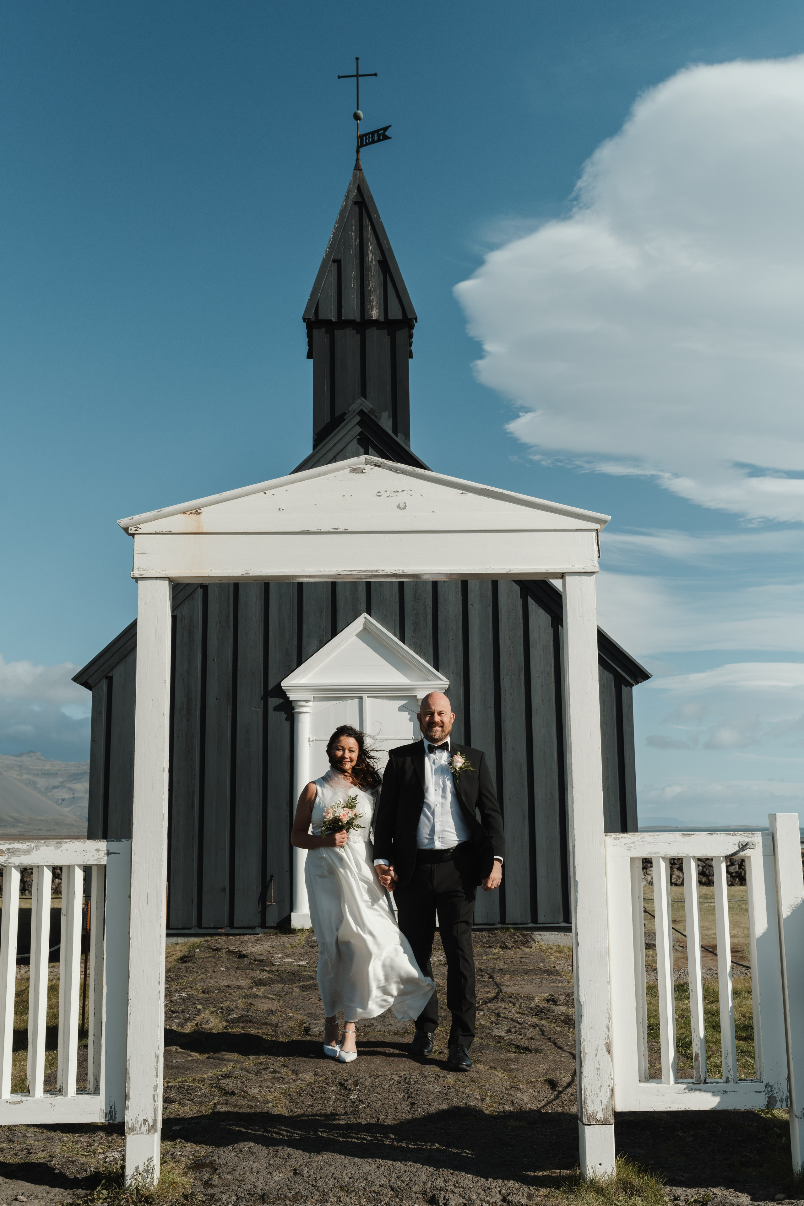 Candid moment of the wedding couple laughing near Búðir Church, surrounded by Iceland’s untamed nature.