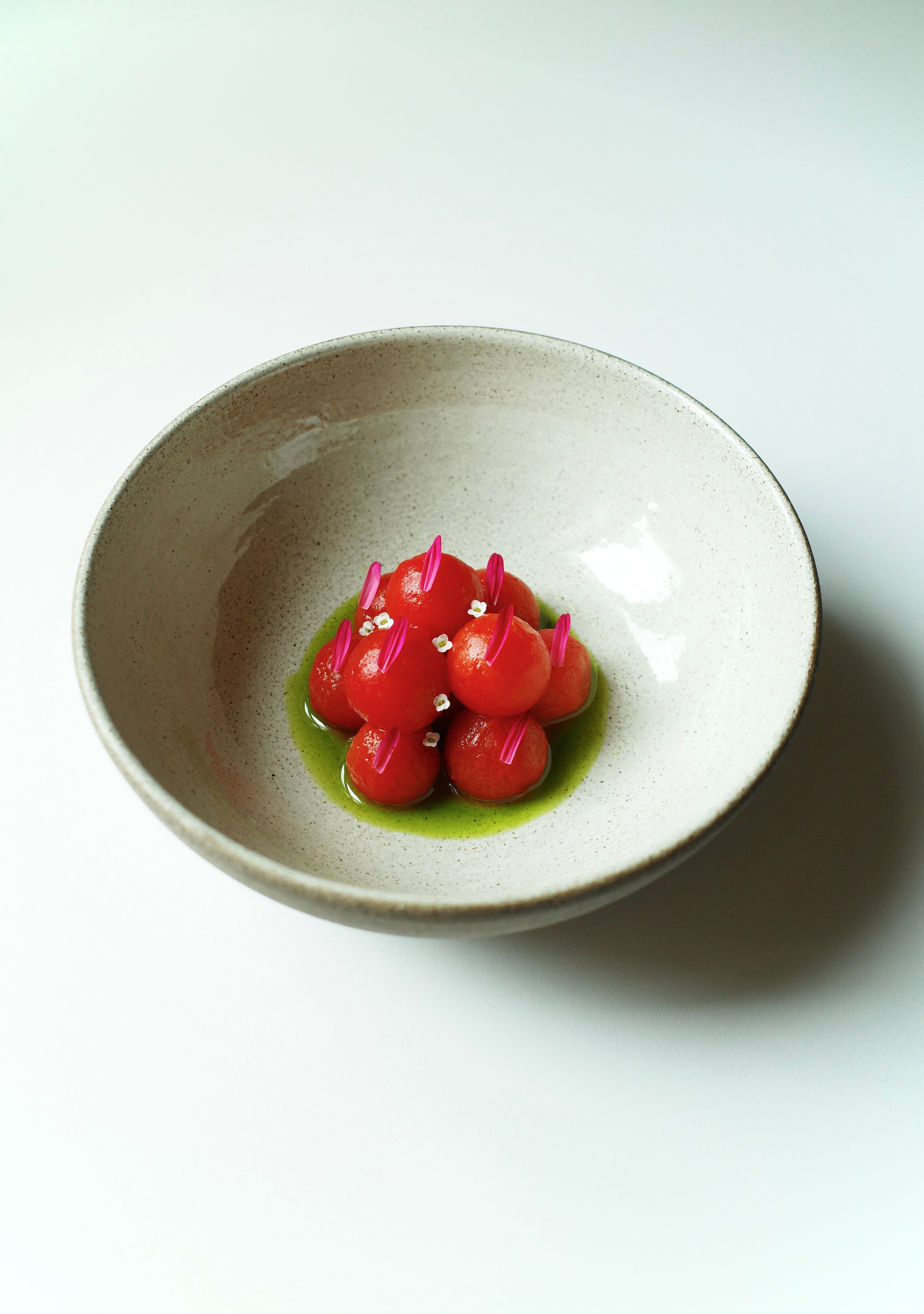 Farm cherry tomatoes, blanched and served with an emulsion of reduced tomato juice and green oil.