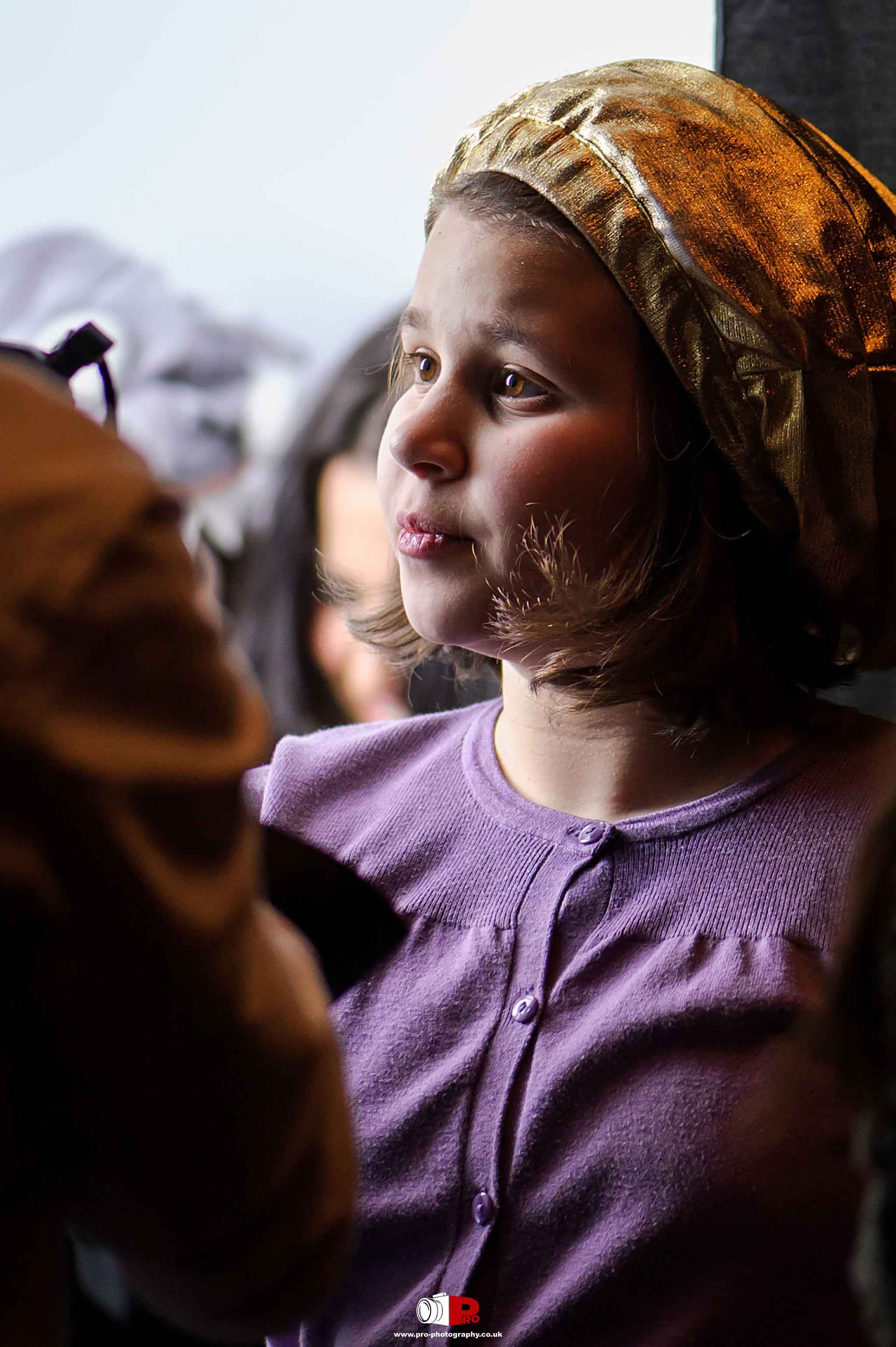 Close-up of a young girl in a purple sweater and gold headpiece at the Hanukkah Festival of Light.