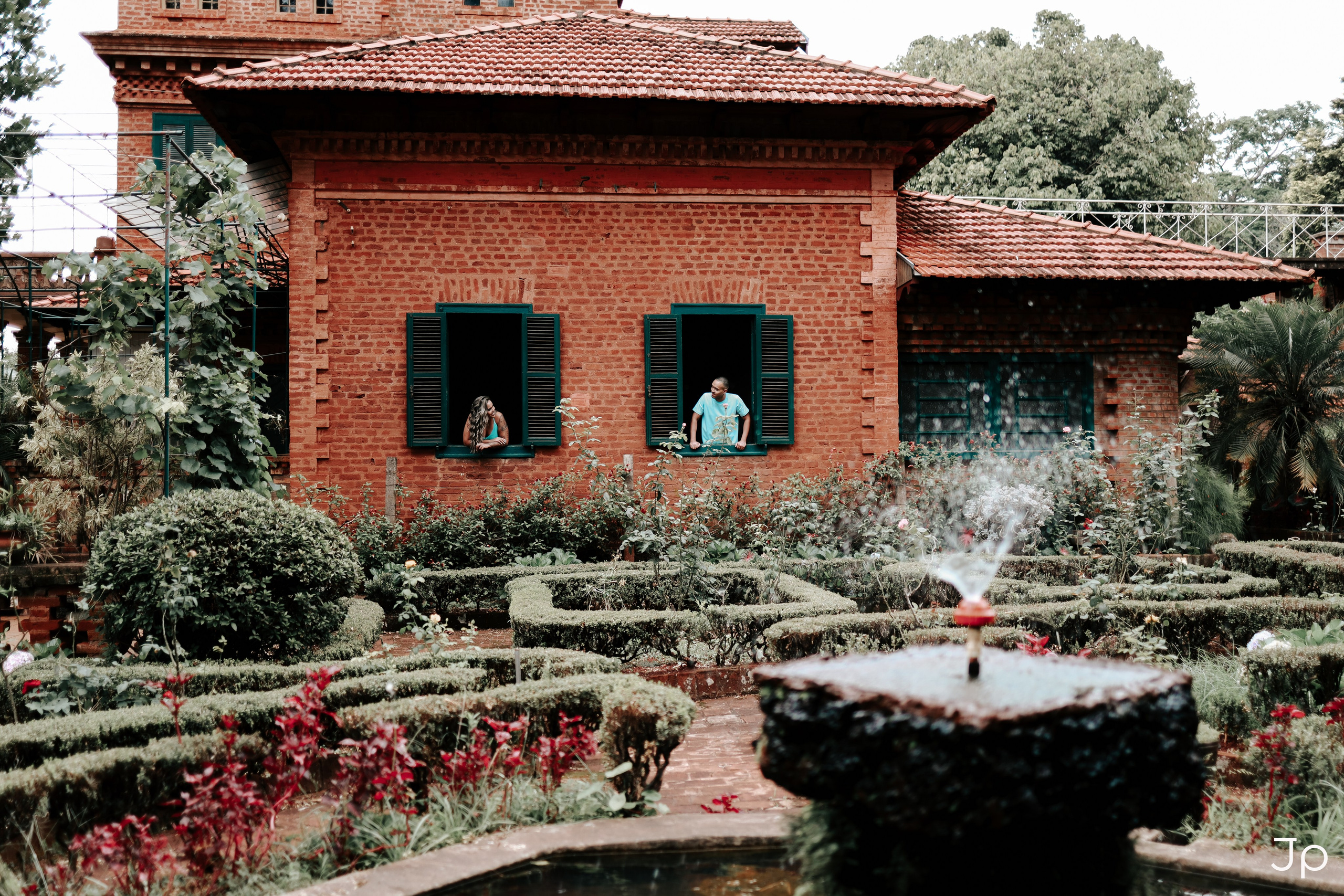 Casal olha pela janela do casarão em Pederneiras durante ensaio fotográfico de casal.