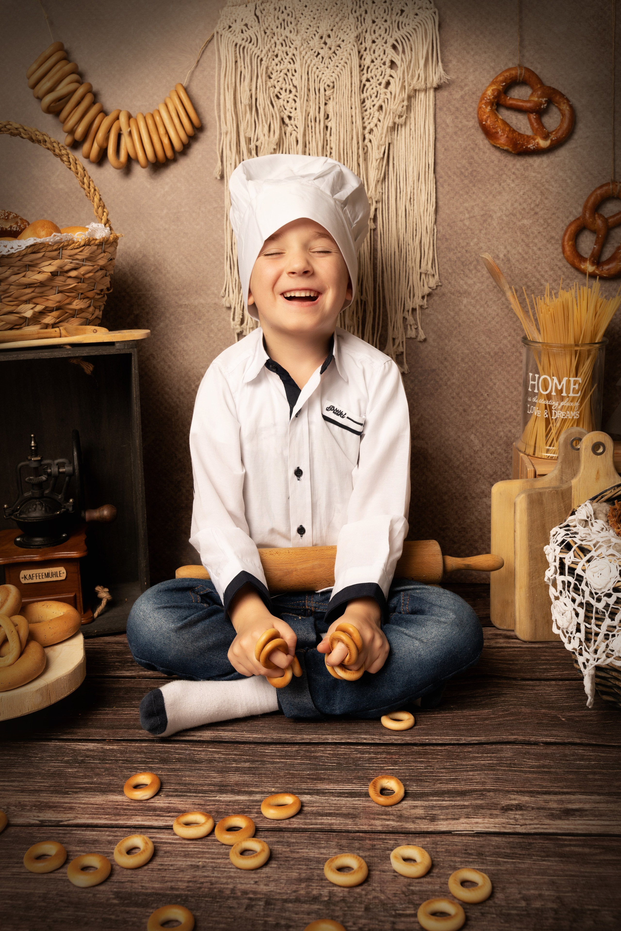 Foto eines als Koch verkleideten Jungen mit Bagels und einem Nudelholz