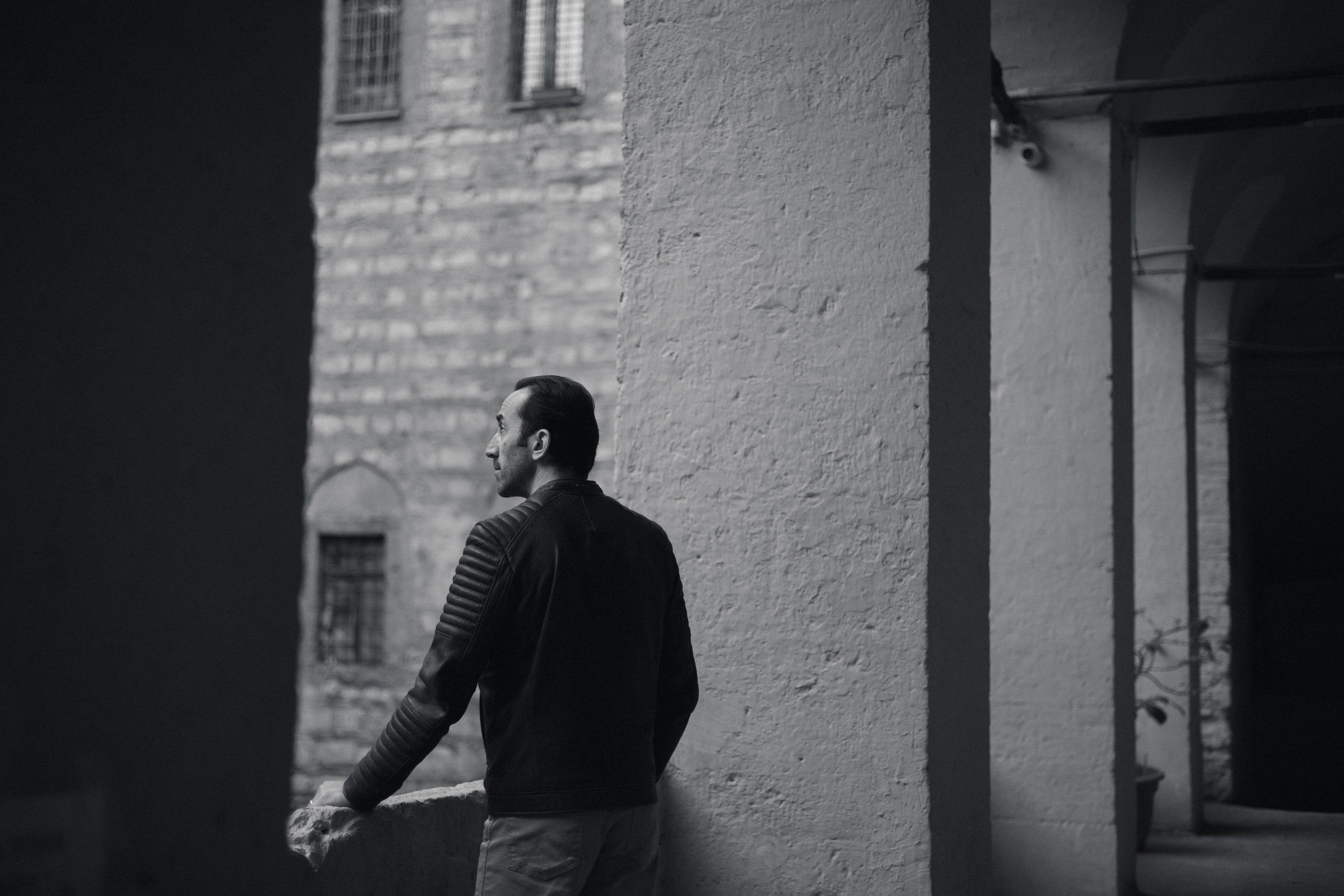 Мужской портрет в Стамбуле, мужчина опирается на каменный парапет старинной аркады и смотрит в сторону.