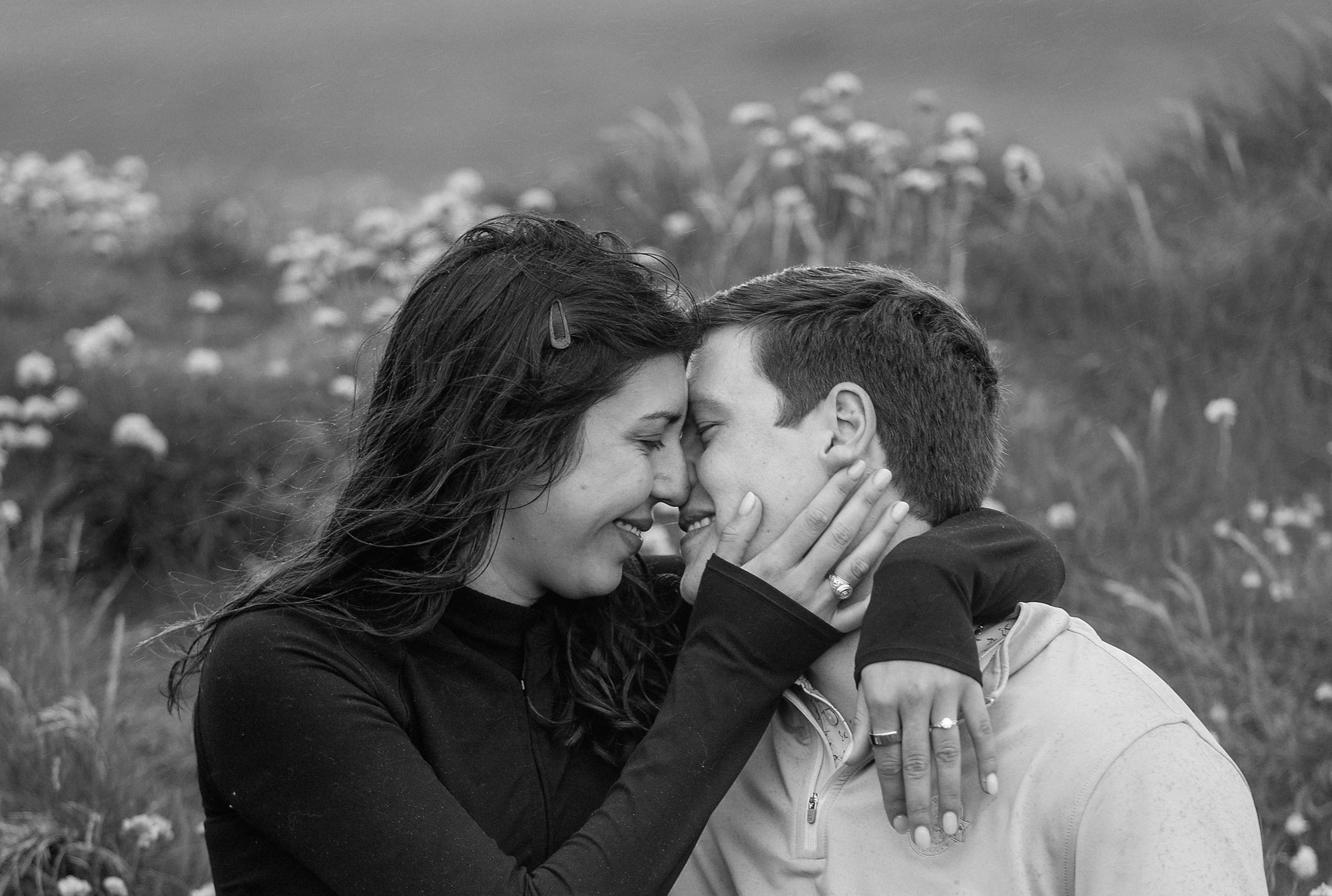A tender, black and white portrait of a couple sharing a quiet, romantic moment in a wildflower field near Dublin.