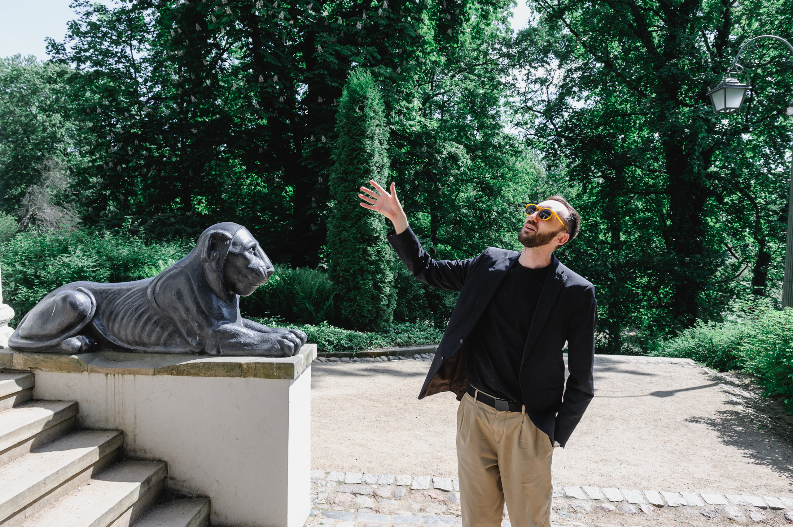 Cultural scholar Dmitry Solodkiy points to the Sibyl's Temple in the Royal Baths with his hand. A sphinx is seen in the background.