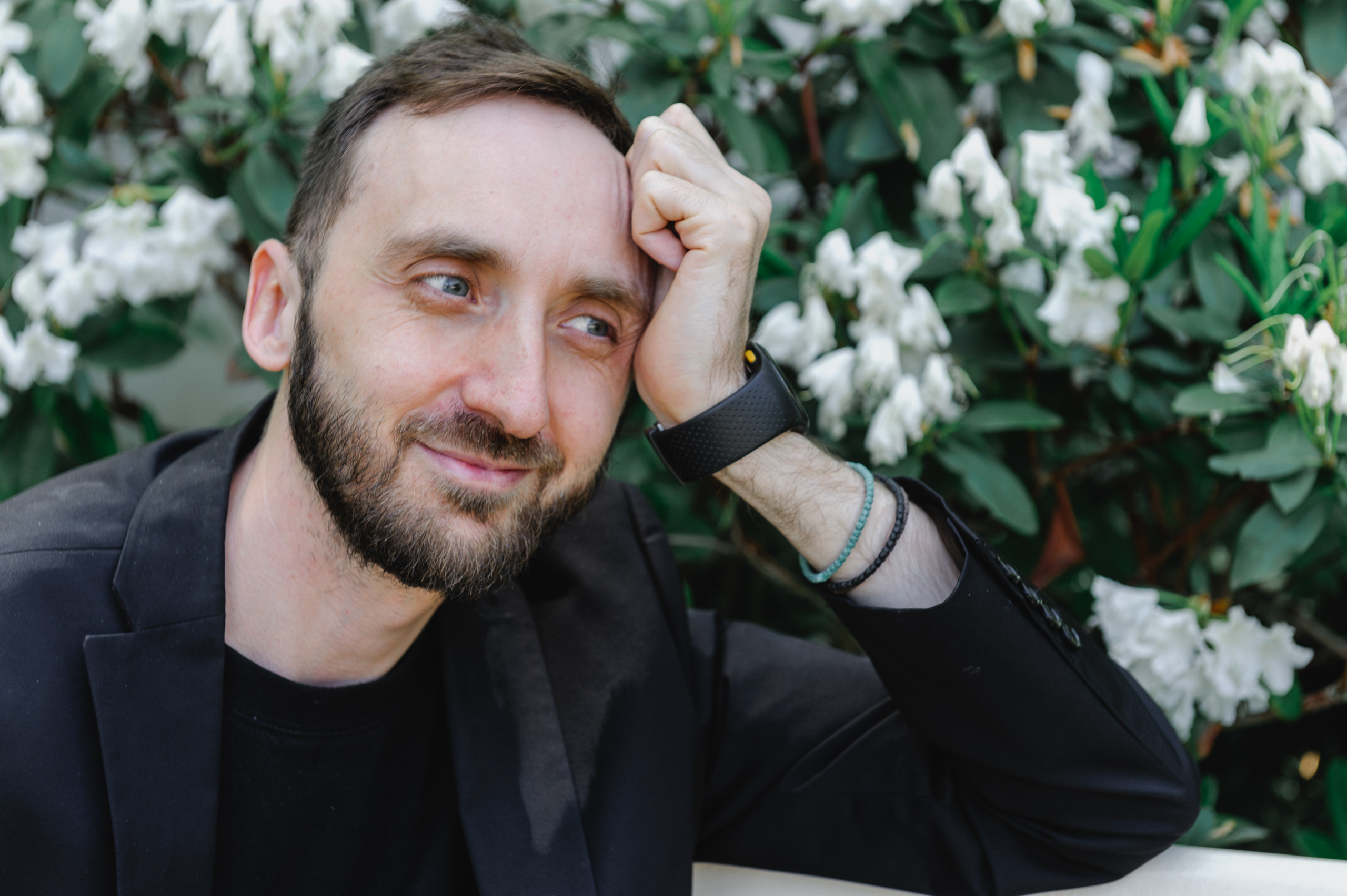 Art historian Dmitry Solodkiy contemplates on a bench against the backdrop of flowers.