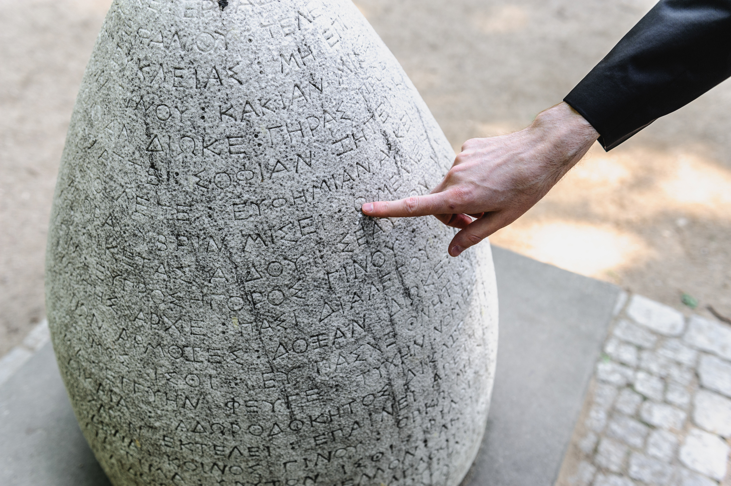 A young man points to a stone tablet with writing.
