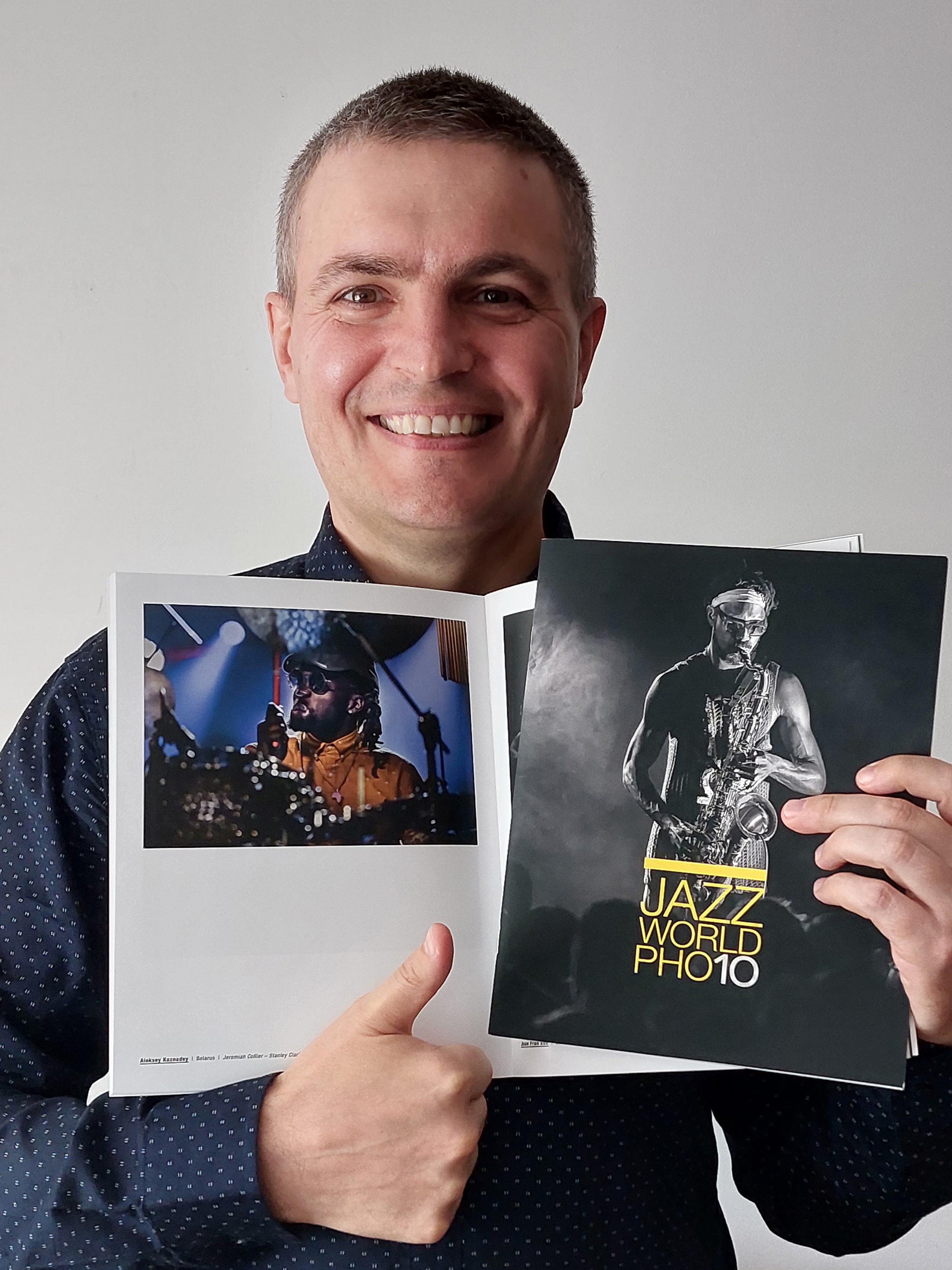 Счастливый Алексей Казнадей с разворотом своей фотографии и обложкой каталога Jazz World Photo'2023