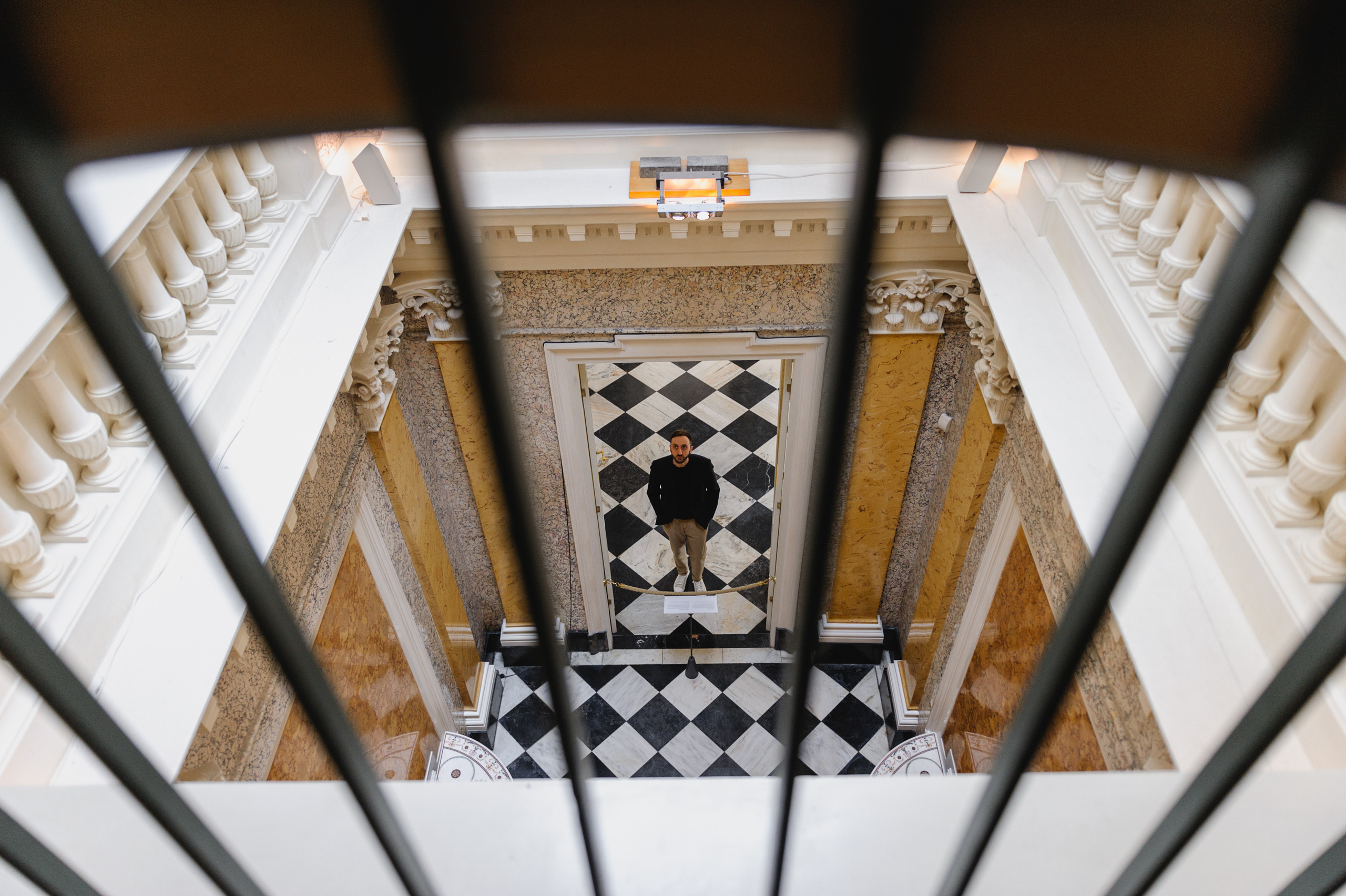 Top view through the bars. A young man stands below. The Royal Baths Museum in Warsaw.