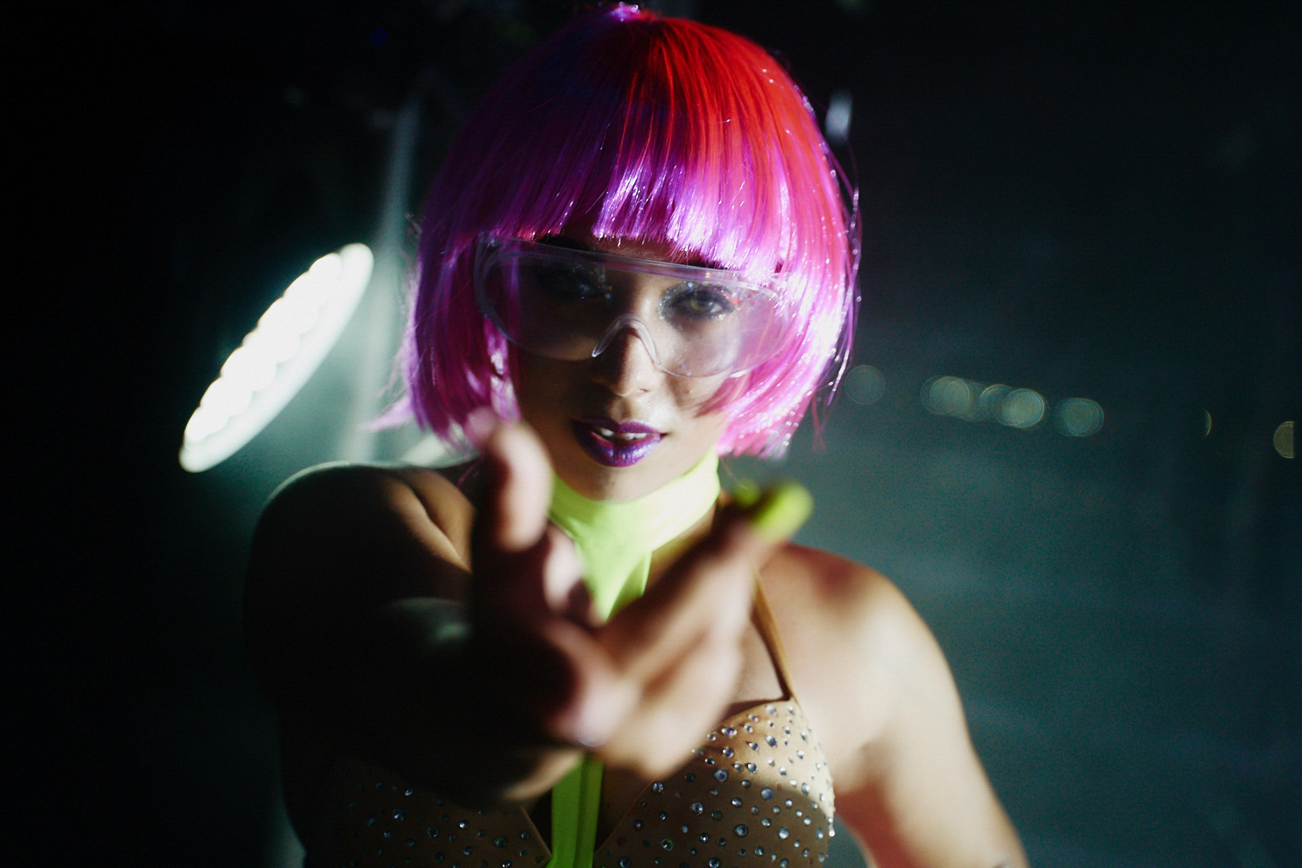 Woman with pink wig and feather headpiece at night event