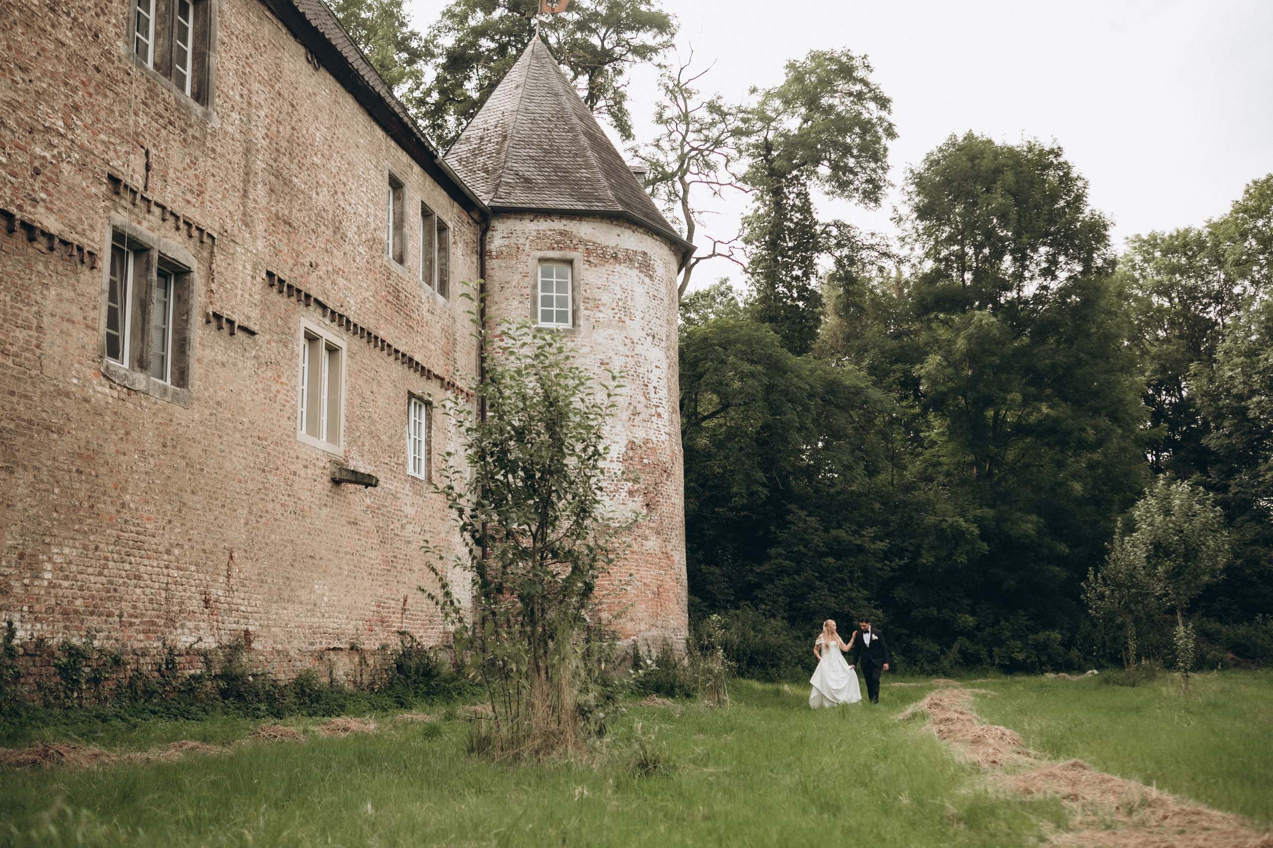 Brautpaar spaziert Hand in Hand in der Nähe von Schloss Hülchrath
