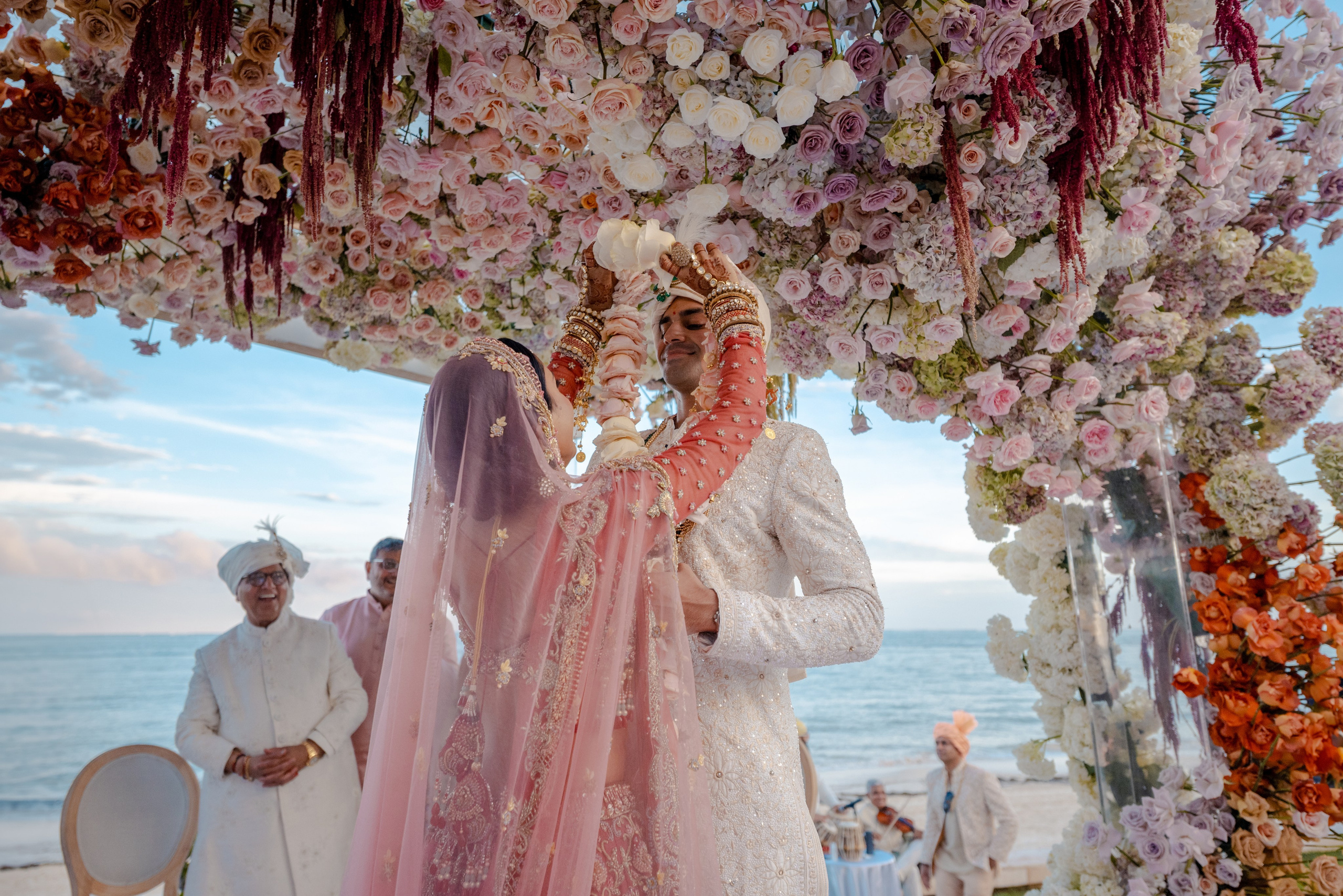 Indian bride placing a floral garland on the groom during the Jai Mala ceremony at Baraat celebration in Cancun