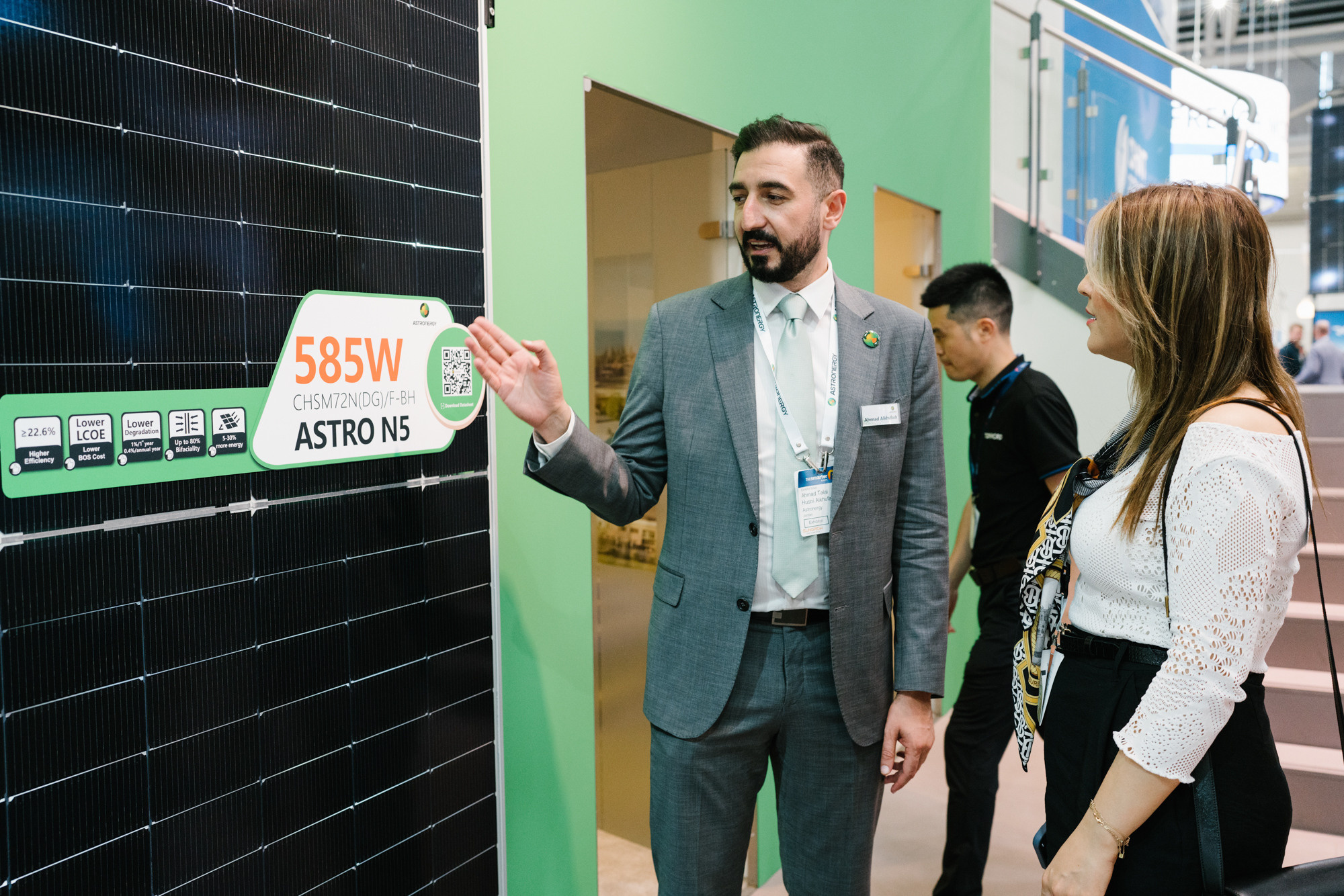 Executive explaining solar panel figures to visitors at the stand