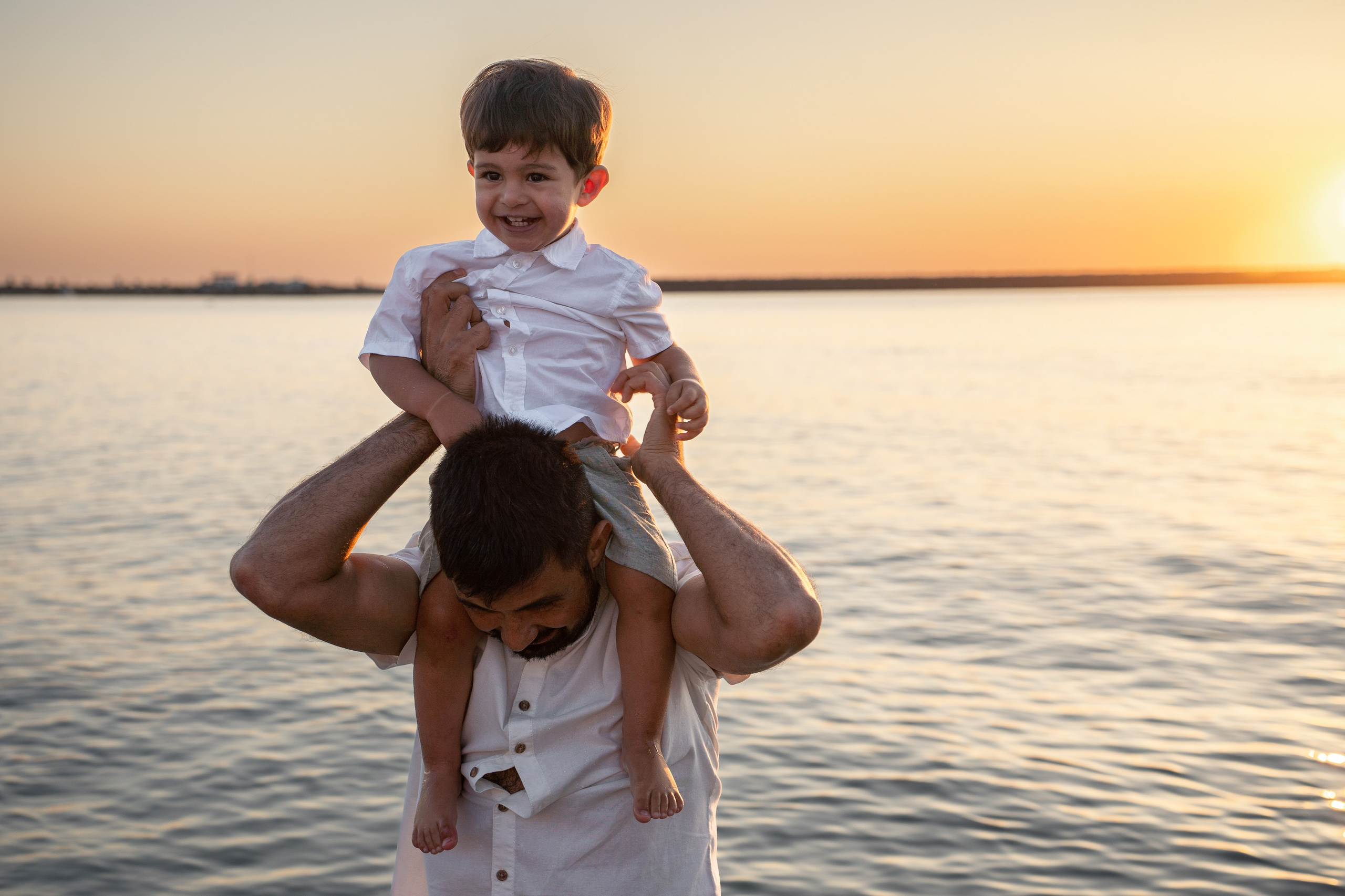 un tata care isi ridica baietelul pe umeri