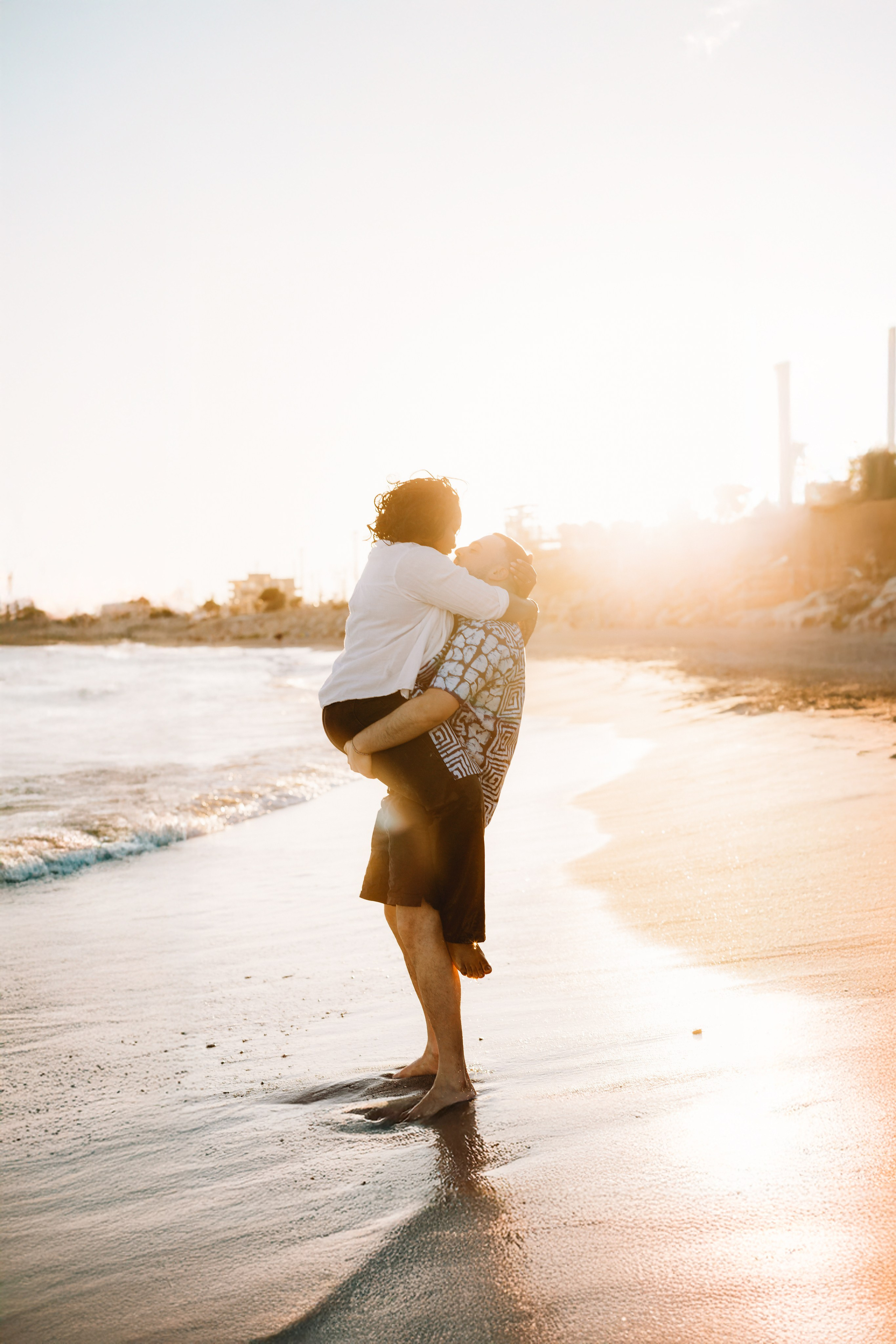 Abrazo romántico en la playa al atardecer durante una sesión de pareja en Valencia, España — perfecto para quienes buscan momentos naturales y llenos de amor capturados profesionalmente a lo largo de la costa española.