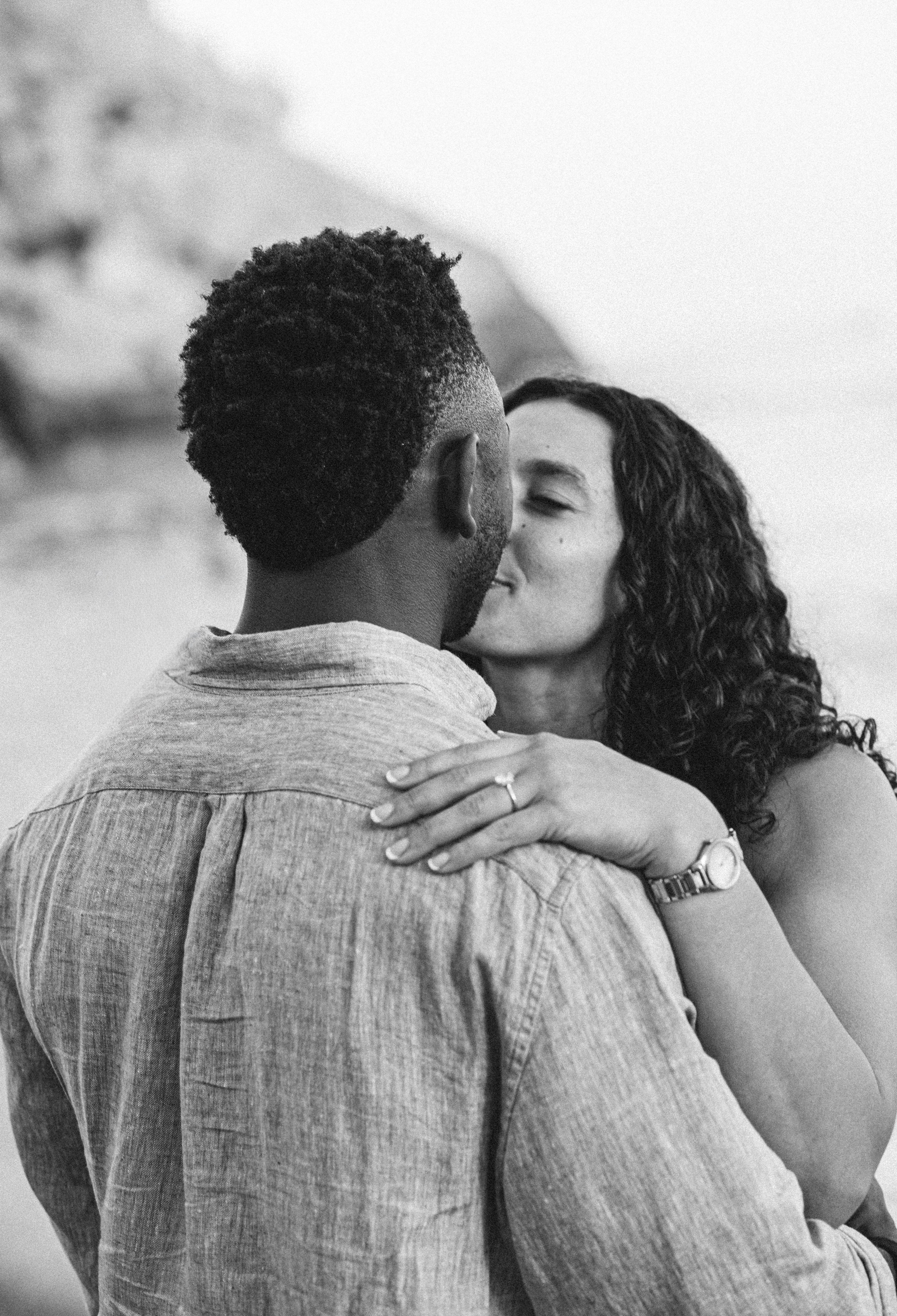 Retrato en blanco y negro de una pareja compartiendo un beso íntimo durante una sesión de historia de amor en la playa de Valencia, España — ideal para mostrar fotografía emocional y atemporal de pareja en Valencia y sesiones románticas en toda España.