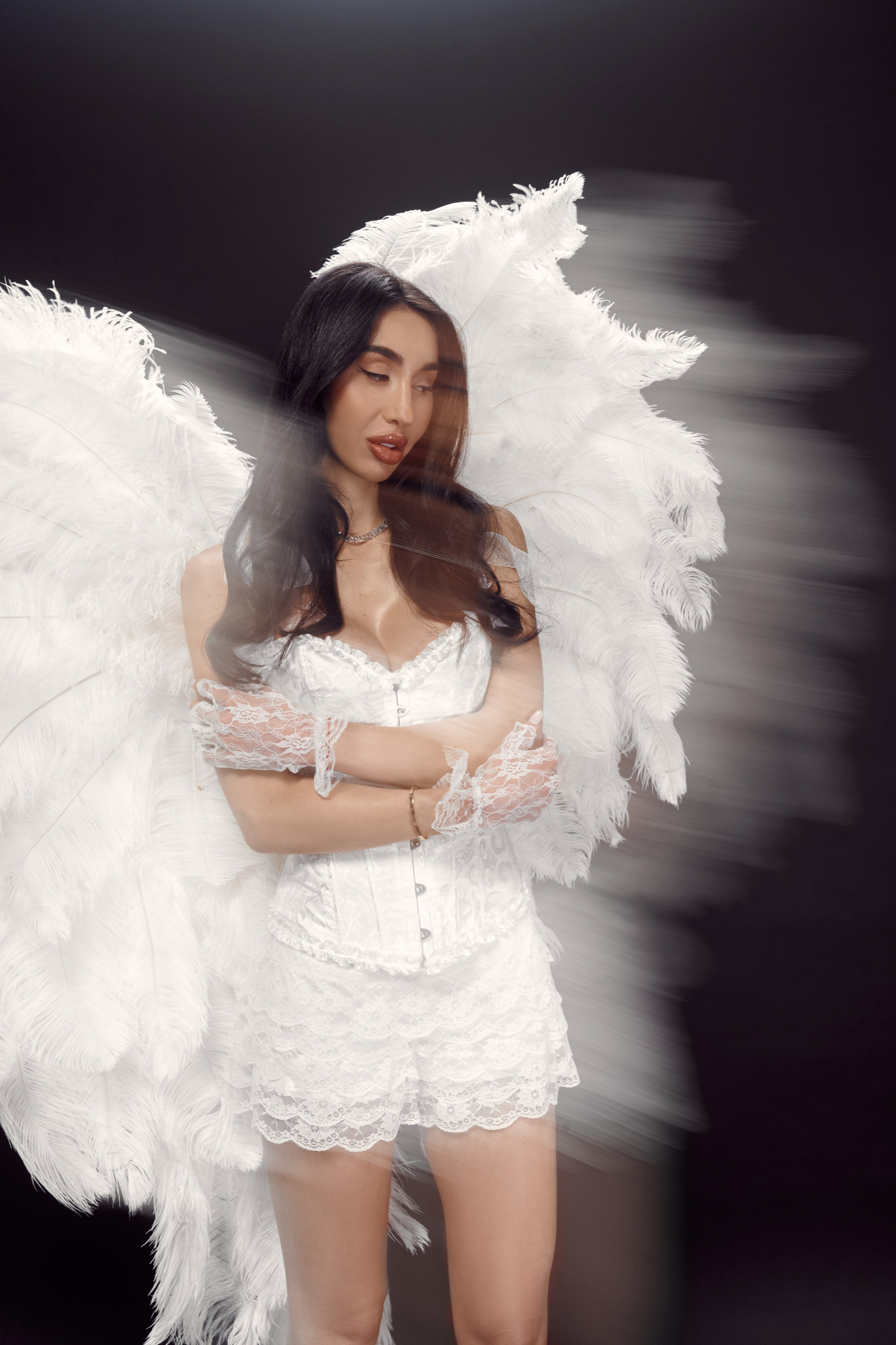 Editorial studio portrait of Ester Rogovaya with feather wings, motion blur and minimalist lighting