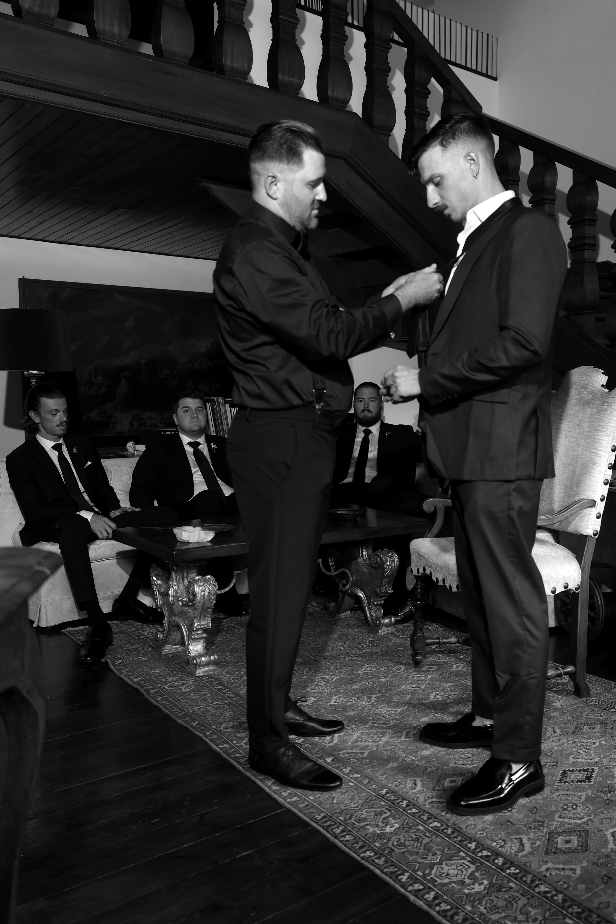Groom adjusting his tie in a classic Italian setting.