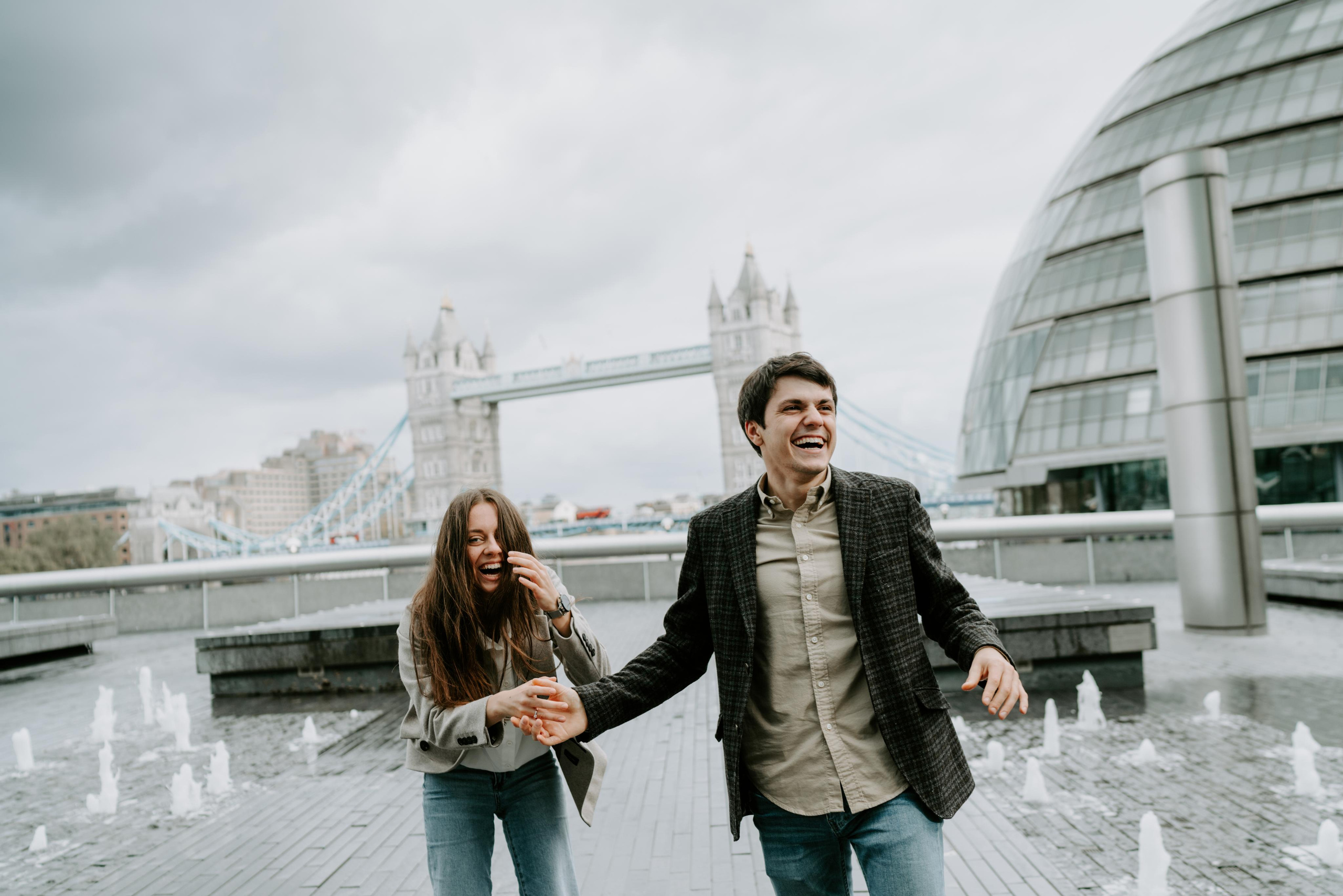 young couple laughing with tower bridge on the background 