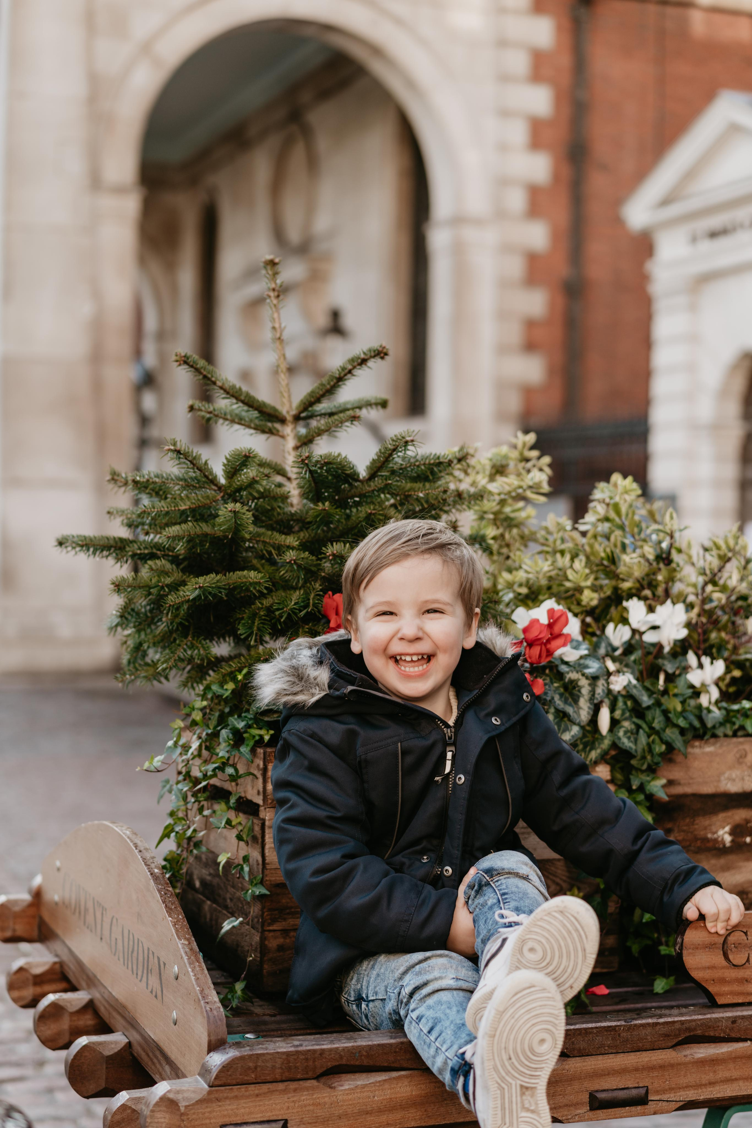 smiling toddler sitting under the  Christmas tree 