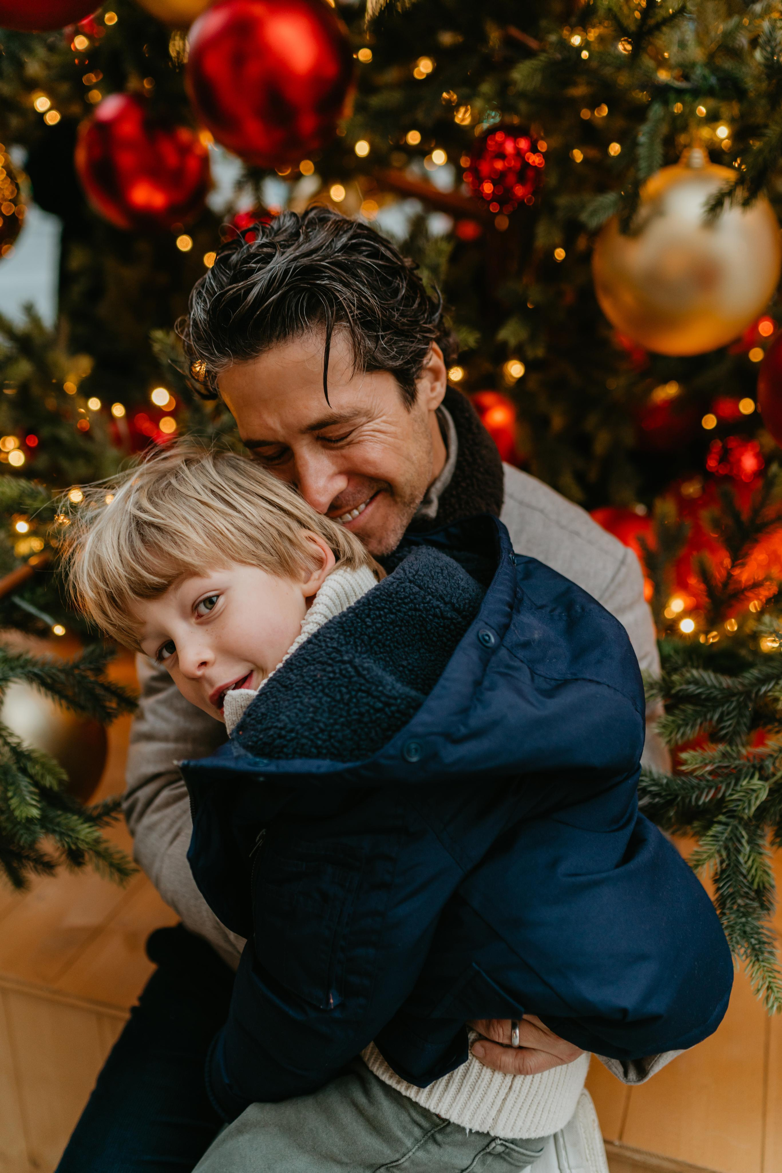 farther hugging his son under Christmas tree