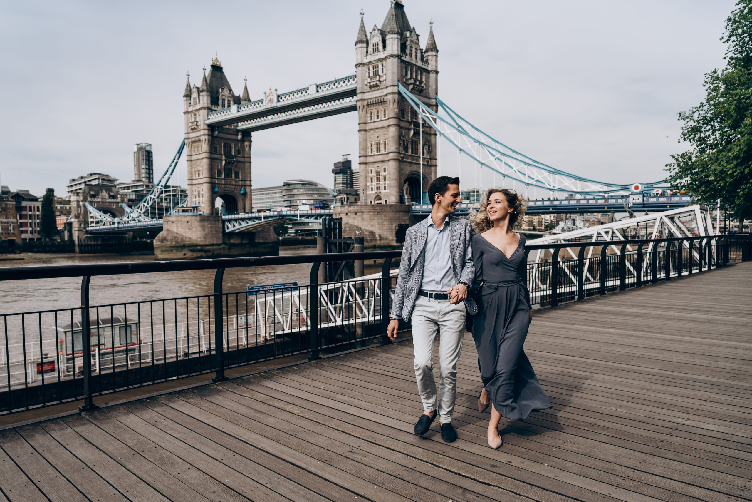 young couple running together holding hands with tower bridge on the background 