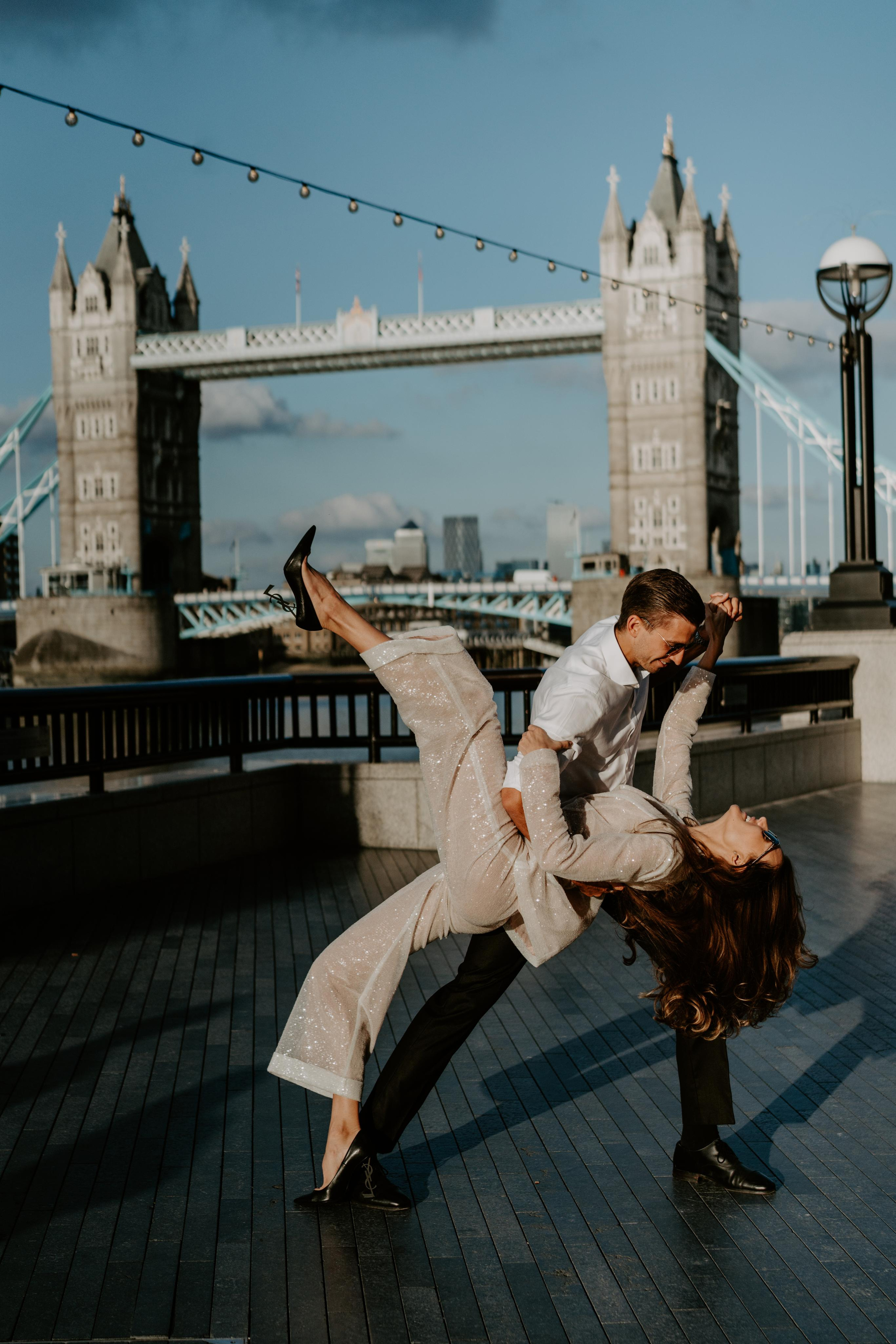 young couple dancing with tower bridge on the background 