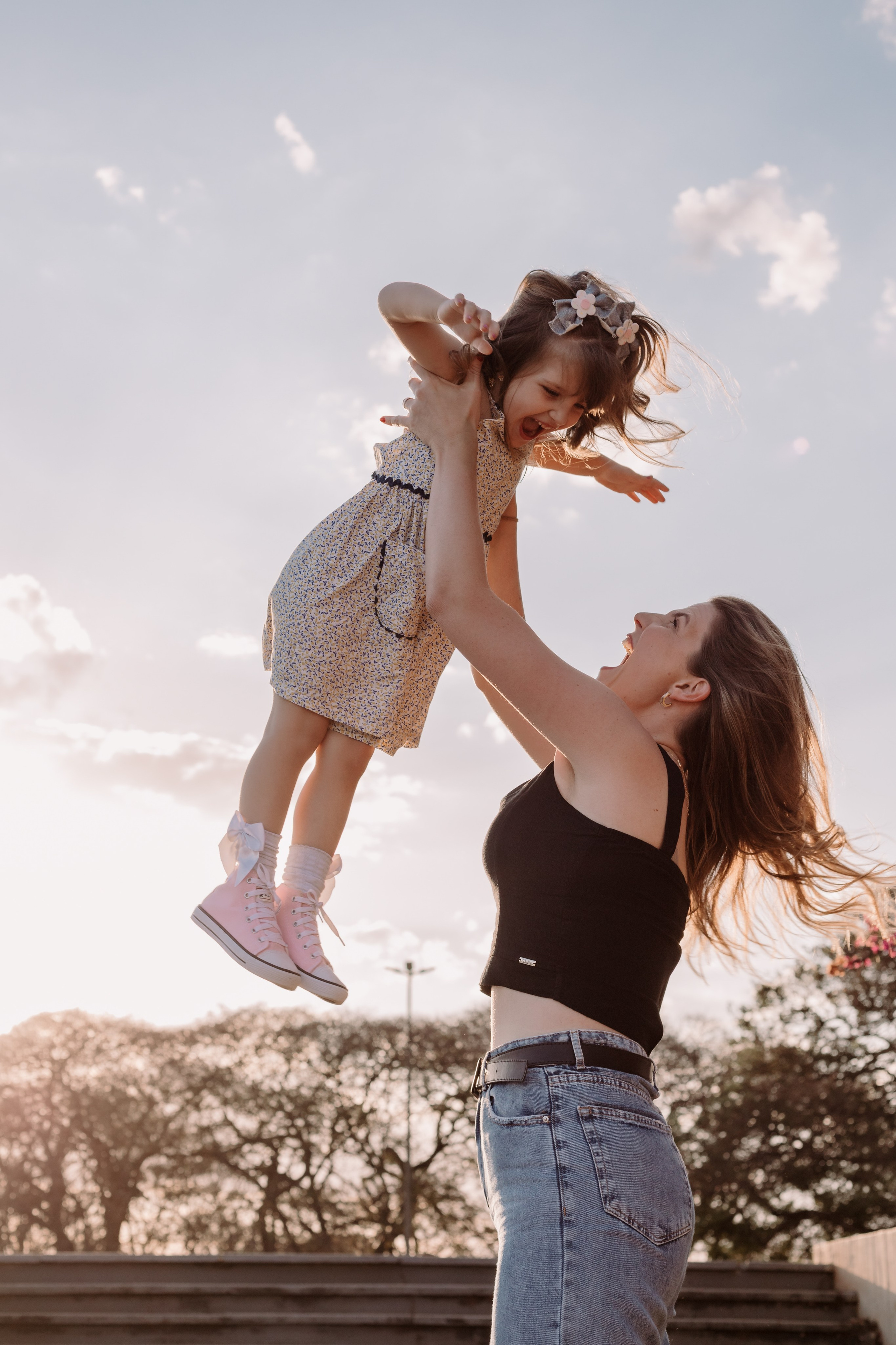 Mãe brincando com a filha com o céu de Brasília ao fundo