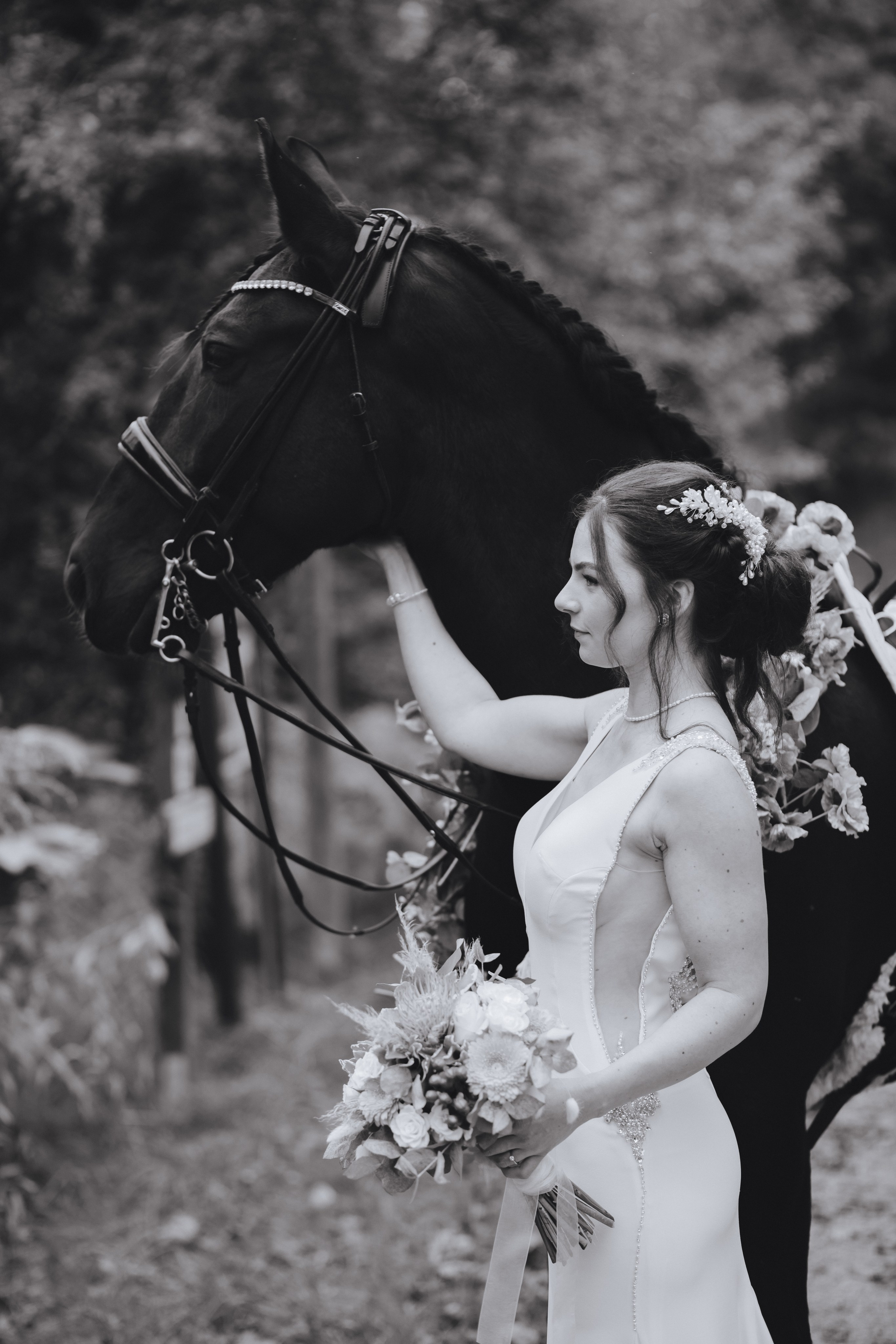 Die Braut und das Pferd schauen gemeinsam nachdenklich in die gleiche Richtung. Romantische Hochzeitsfotos.