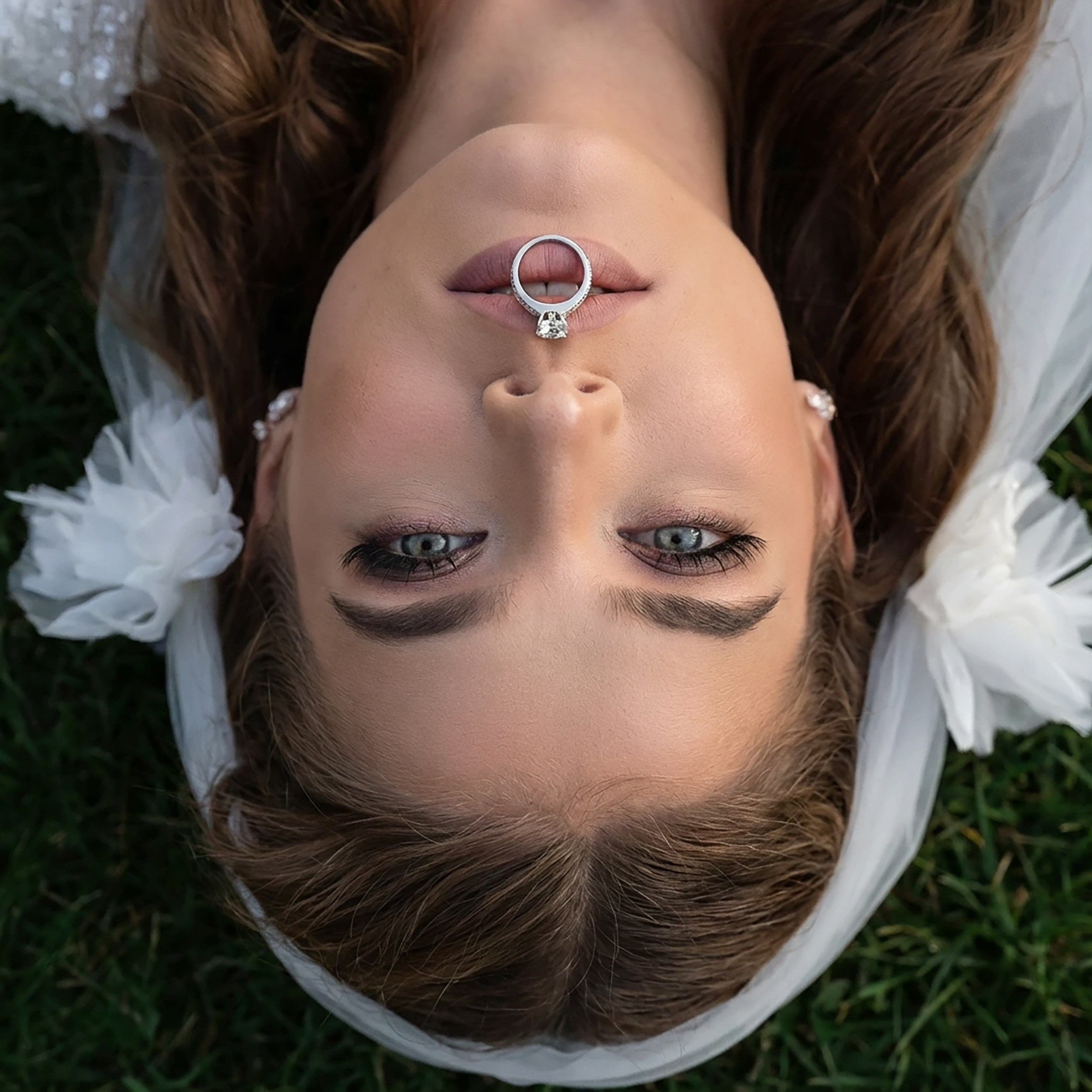 Creative overhead close-up portrait of a bride lying down, balancing her wedding ring on her nose. Fine art wedding photography services in Dublin and Galway by vdphotoart.
