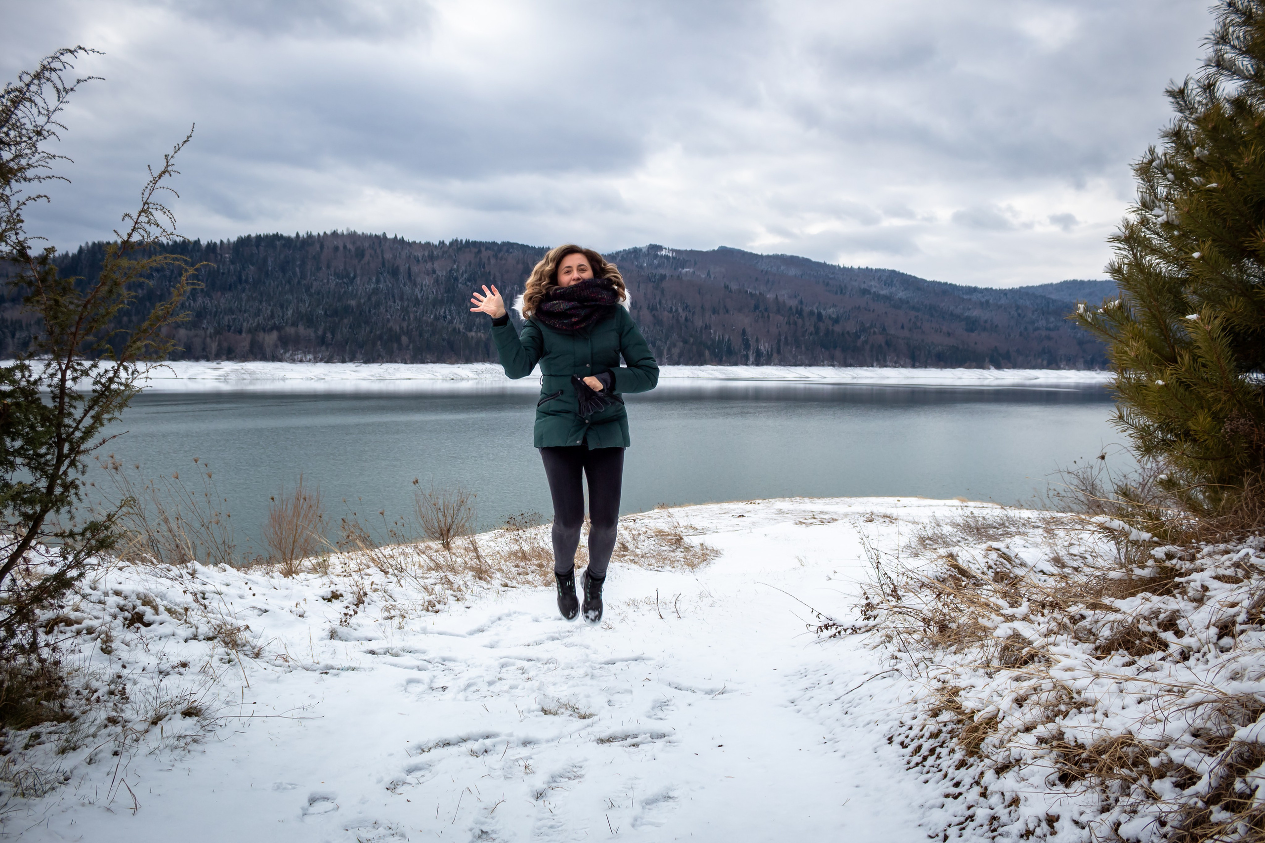 Person walking across a frozen lake under an overcast sky in winter.