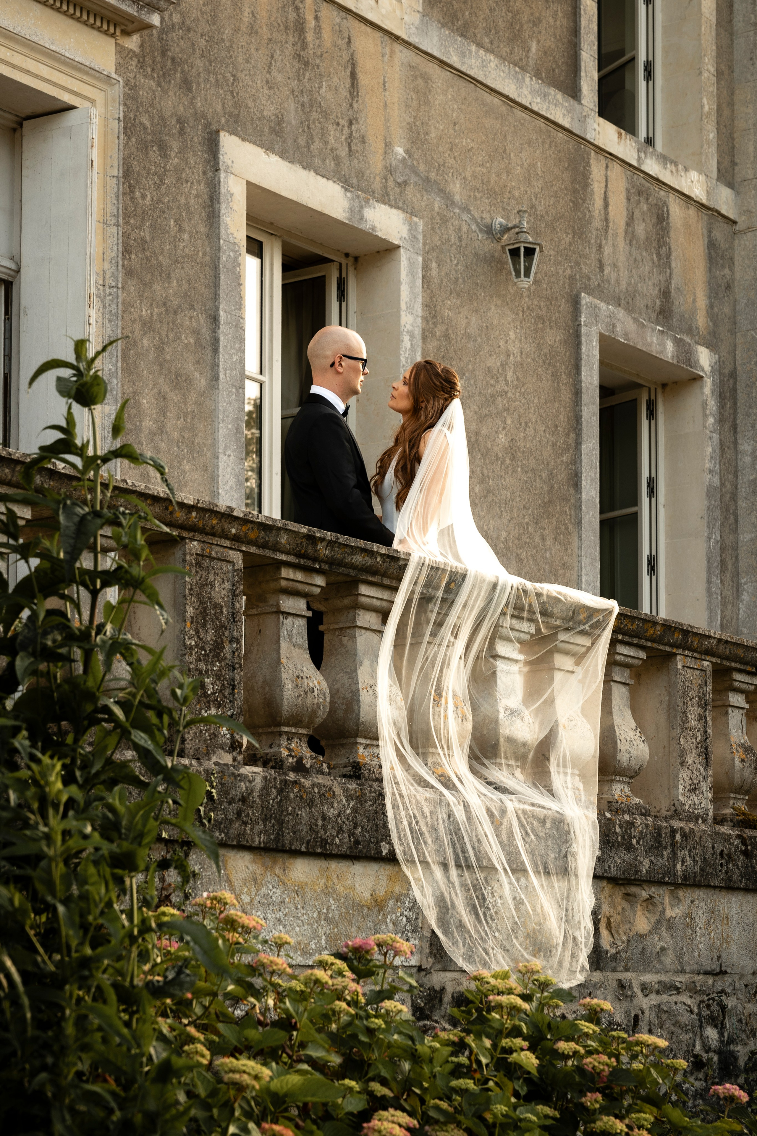 Bride on the château steps with her veil lifting in the wind