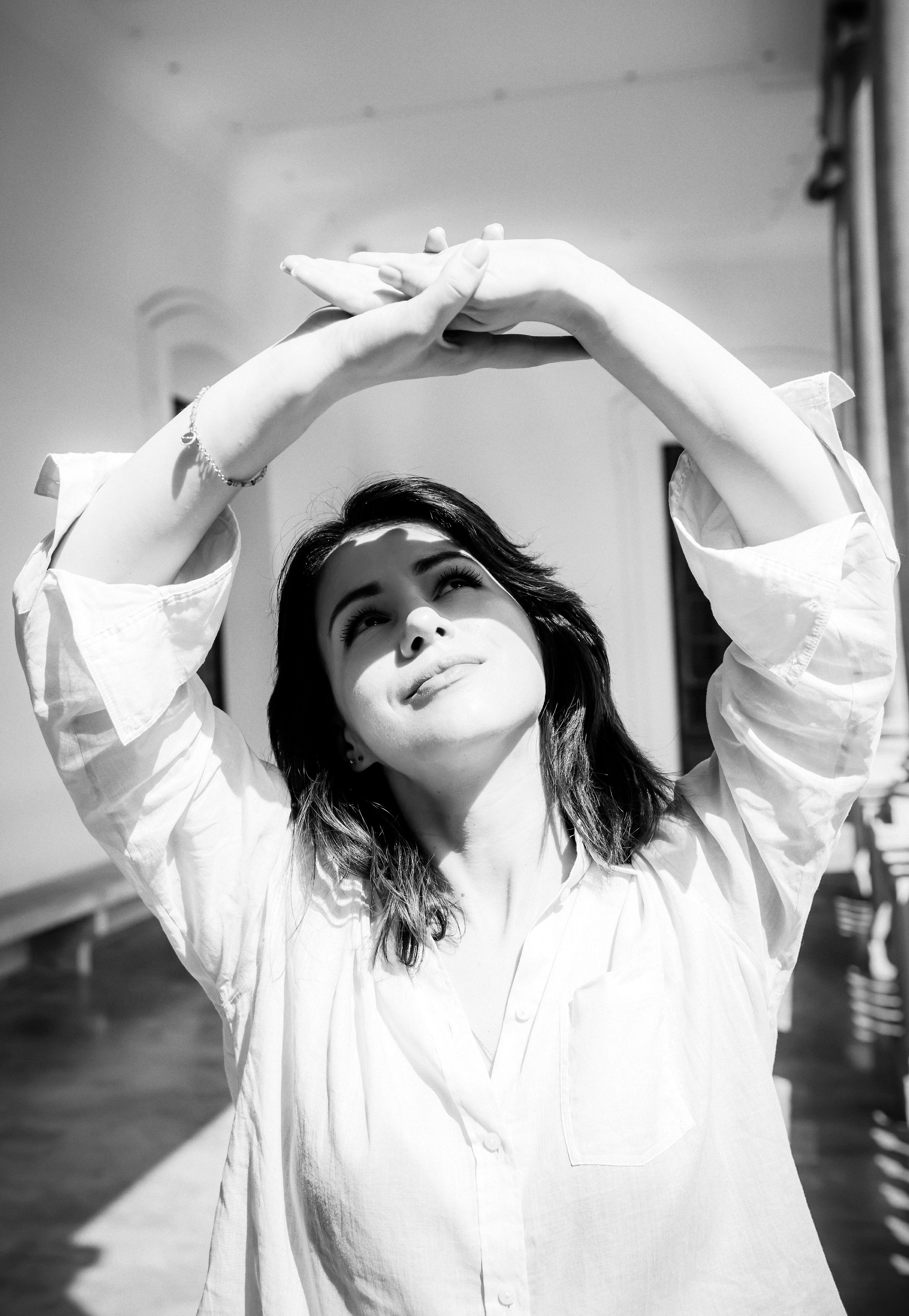 Арт-портрет женщины в помещении, тянущей руки вверх в мягком естественном свете в Мадриде, Испания — вдохновляющий пример элегантной лайфстайл и портретной фотографии в Мадриде и центральной Испании.