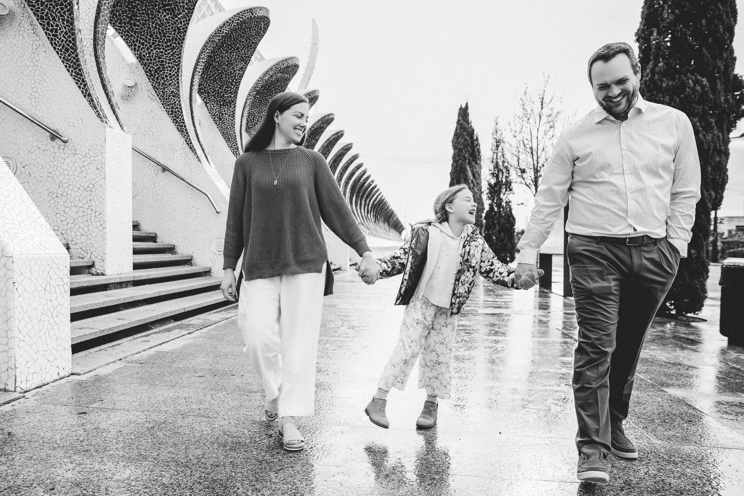 Семейная фотосессия в Валенсии, Испания, где семья гуляет рядом с современными архитектурными достопримечательностями, снято в чёрно-белом стиле для естественного, lifestyle и документального семейного момента — идеально для семейных фотосессий в Валенсии и по всей Испании.