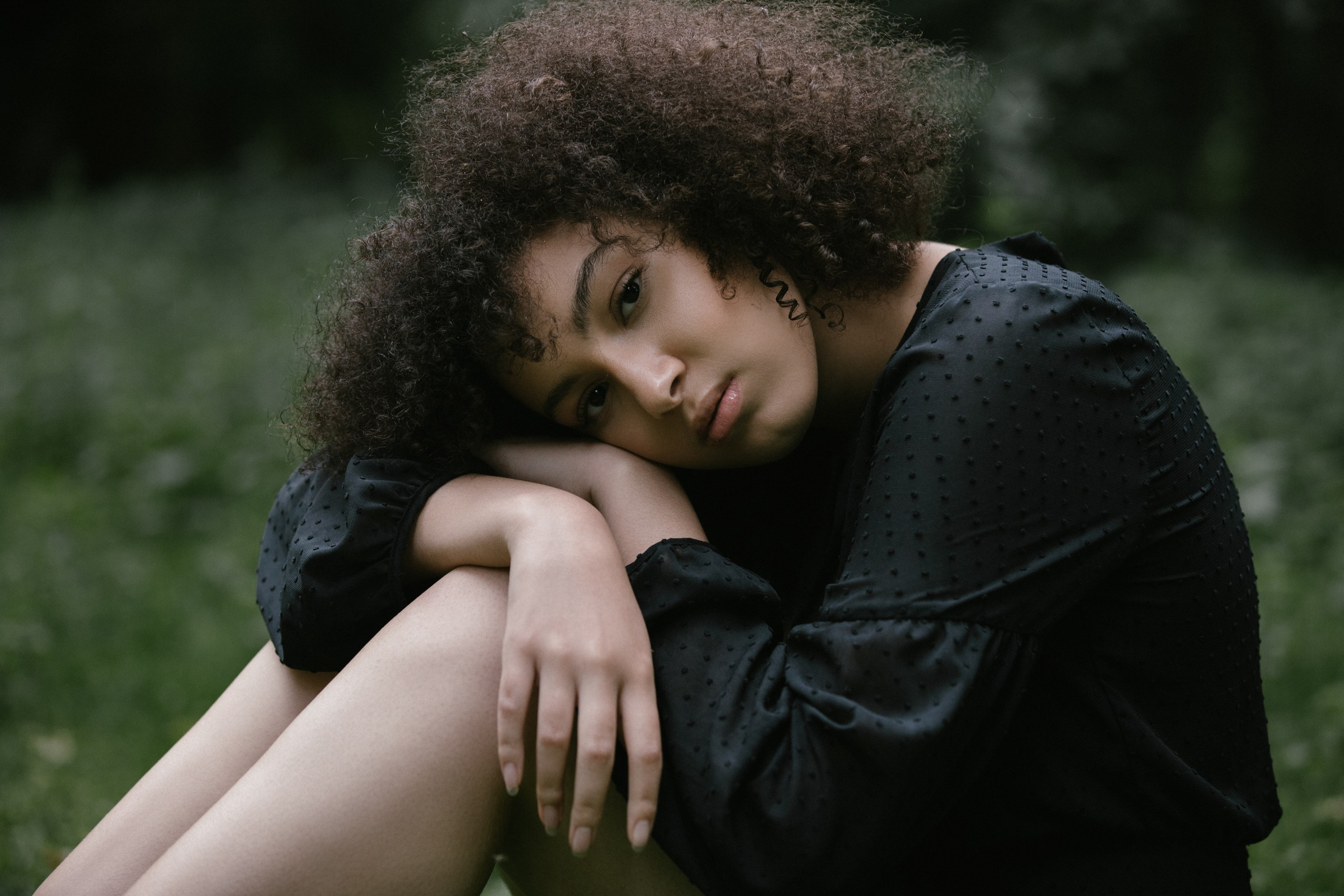 Outdoor-Porträt, Frau ruht mit Kopf auf Armen, sitzend