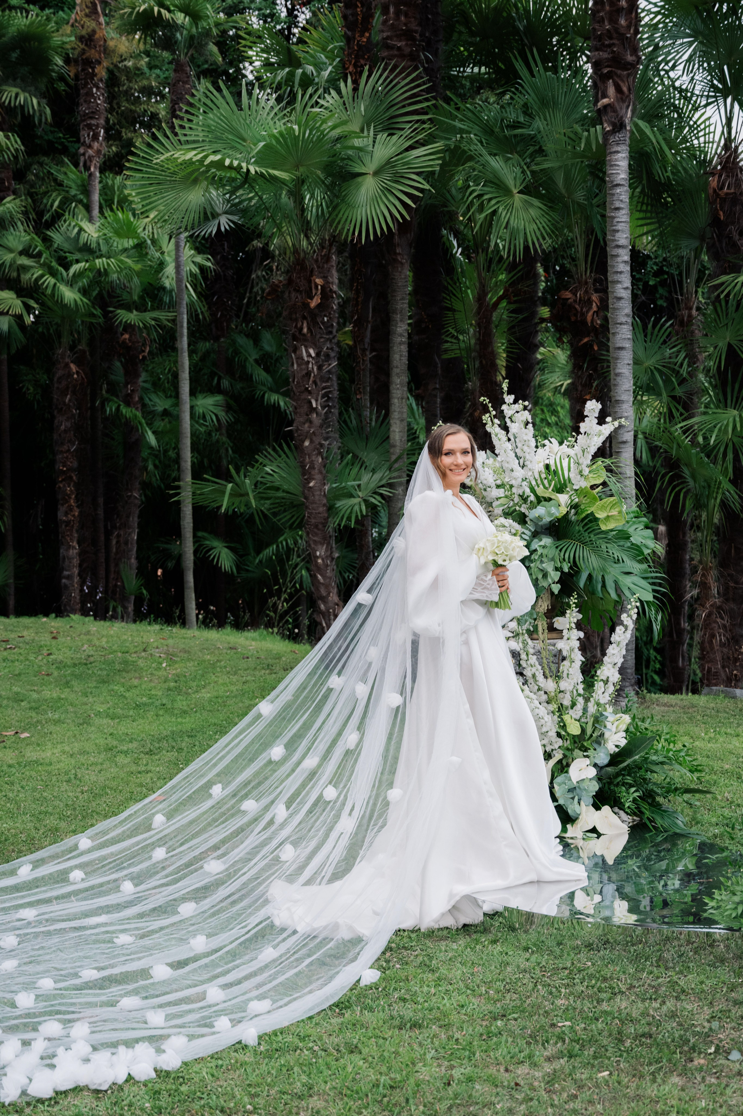 a bride in a white wedding dress and veil with a bouquet
