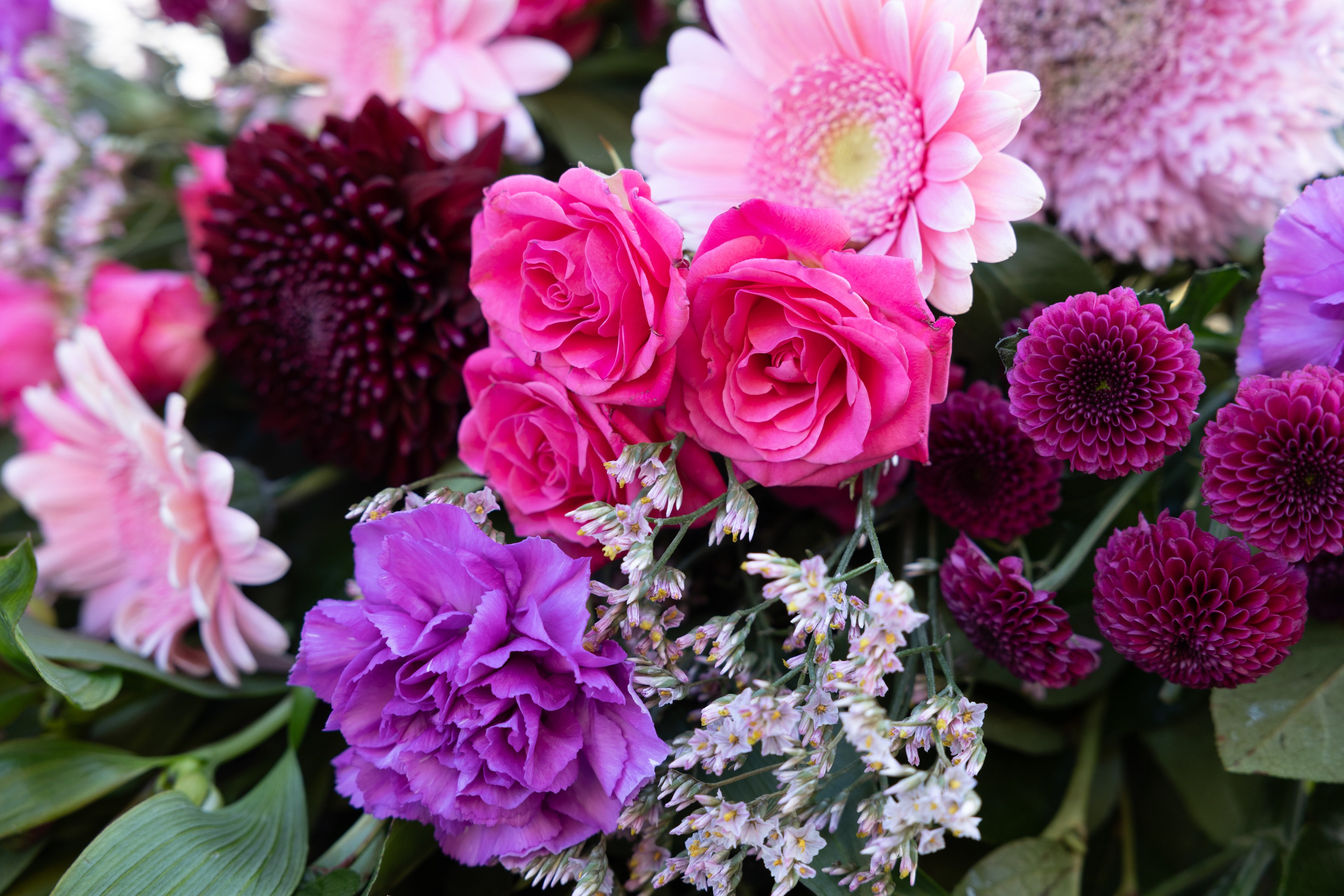 En let og luftig bårebuket, hvor blomsterne er bundet i liggende position. Hver blomst fremhæves smukt med varierede grønt imellem. Bårebuketten er bundet med pink, hvilket lyser ethvert kirkegulv i enhver sæson.