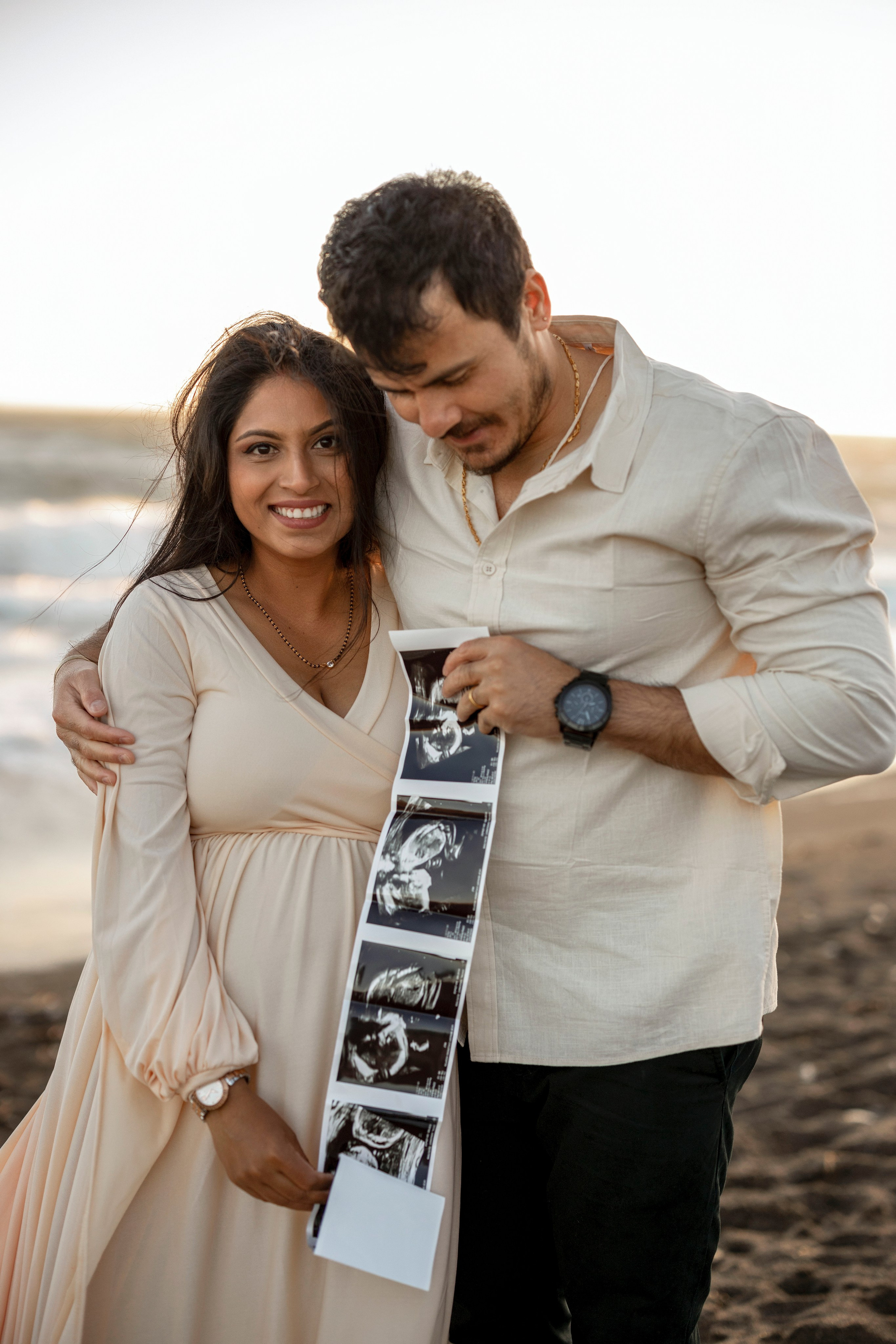 Intimate maternity shoot by the sea with future parents smiling