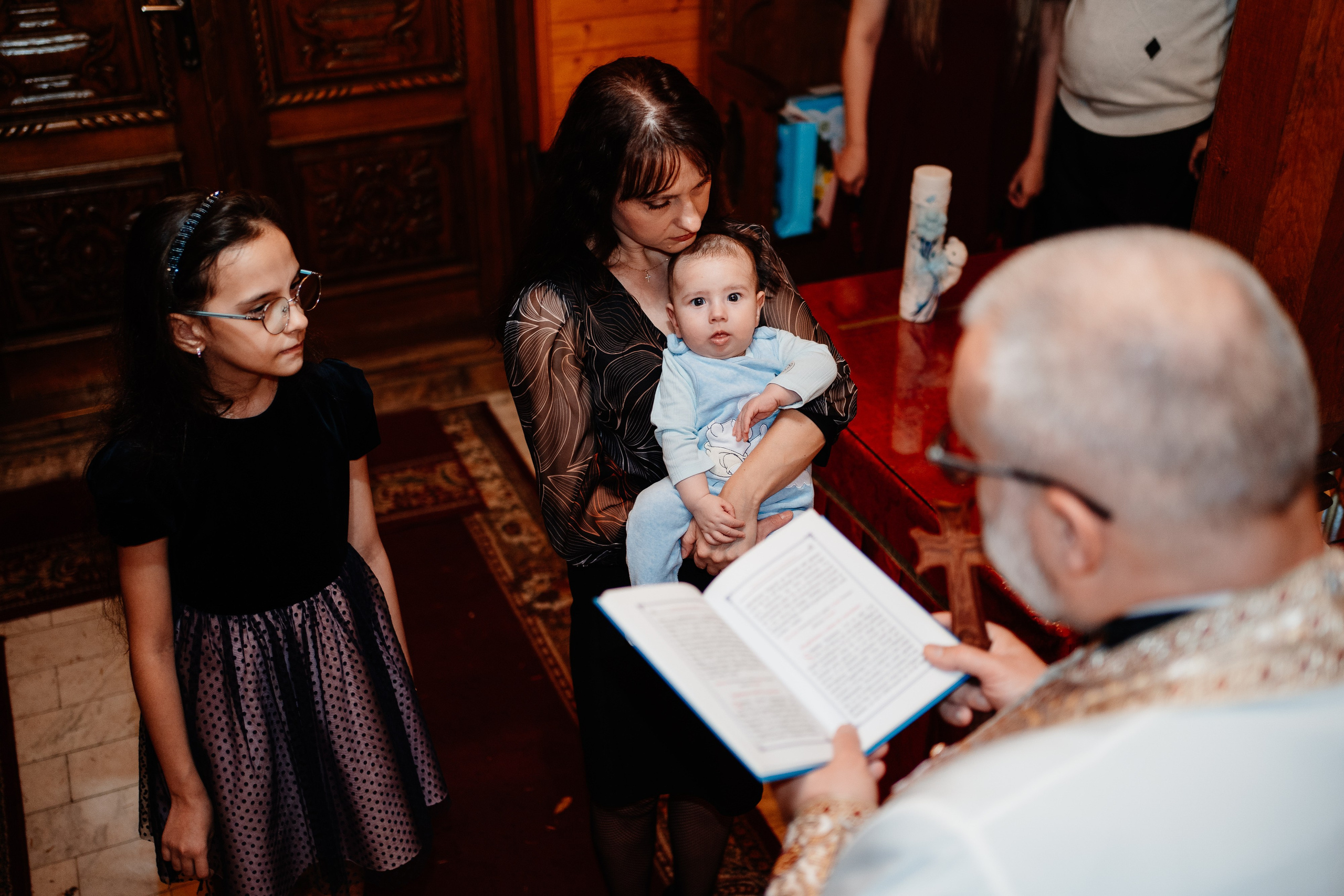 Instantaneu plin de tandrețe dintre părinți și bebeluș în ziua botezului, realizat în Bucuresti. Fotografie profesională de botez, capturând emoțiile autentice ale familiei într-un decor luminos și cald