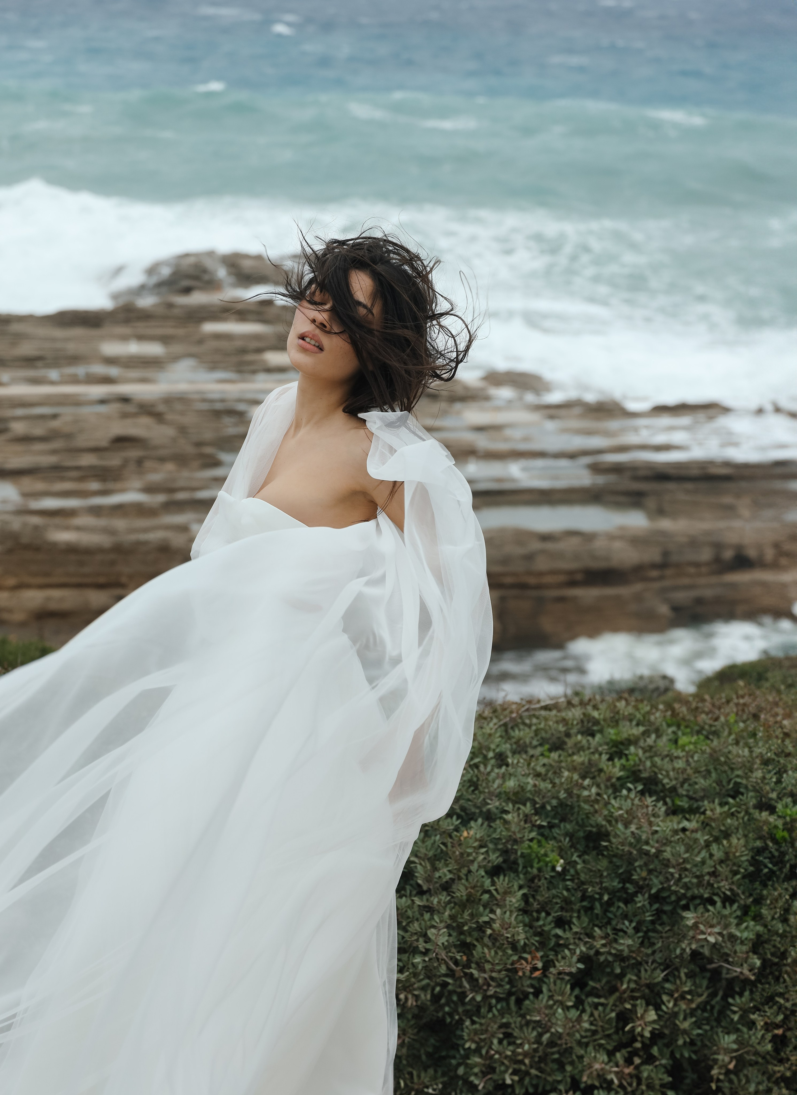 An art photo shoot of a girl in a wedding dress on the windy Kalithea beach in Rhodes, Greece
