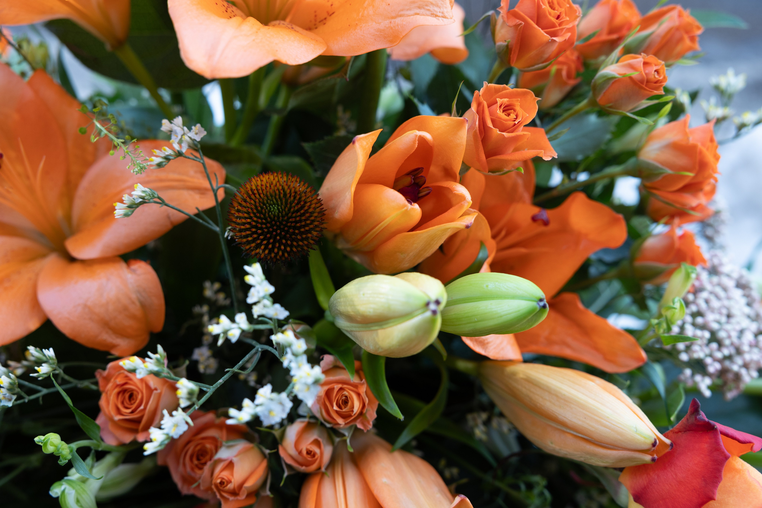 En elegant klassiker til den sidste afsked. Årstidens blomstersorter i høj og flot dekoration. Fastgjort på en grøn thujakrans. Denne krans med forskellige blomster tager sig smukt ud på kirkegulvet.