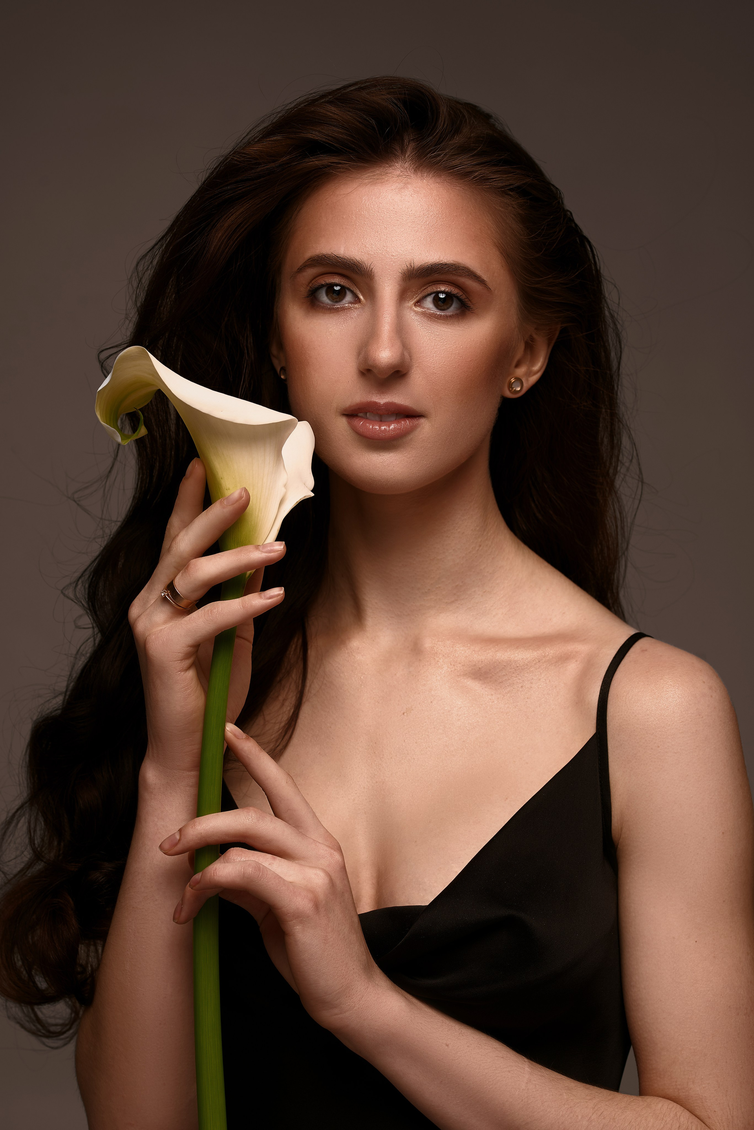 Portret kobiety z długimi, falującymi włosami trzymającej elegancką kalię – subtelna i romantyczna sesja zdjęciowa w Warszawie