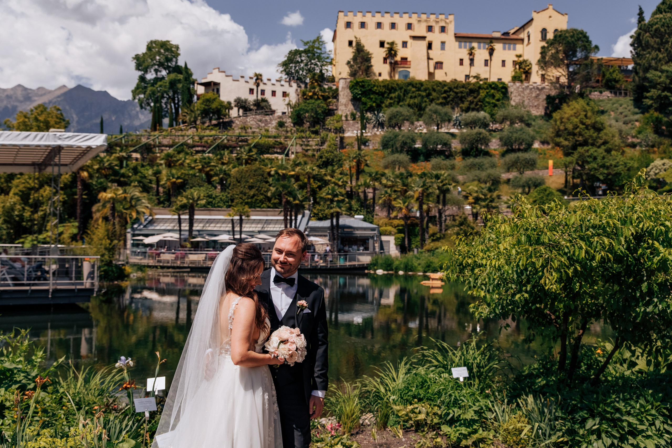 Der Bräutigam und die Braut stehen vor dem Schloss Trauttmansdorff, umgeben von einer romantischen Atmosphäre und atemberaubender Architektur.