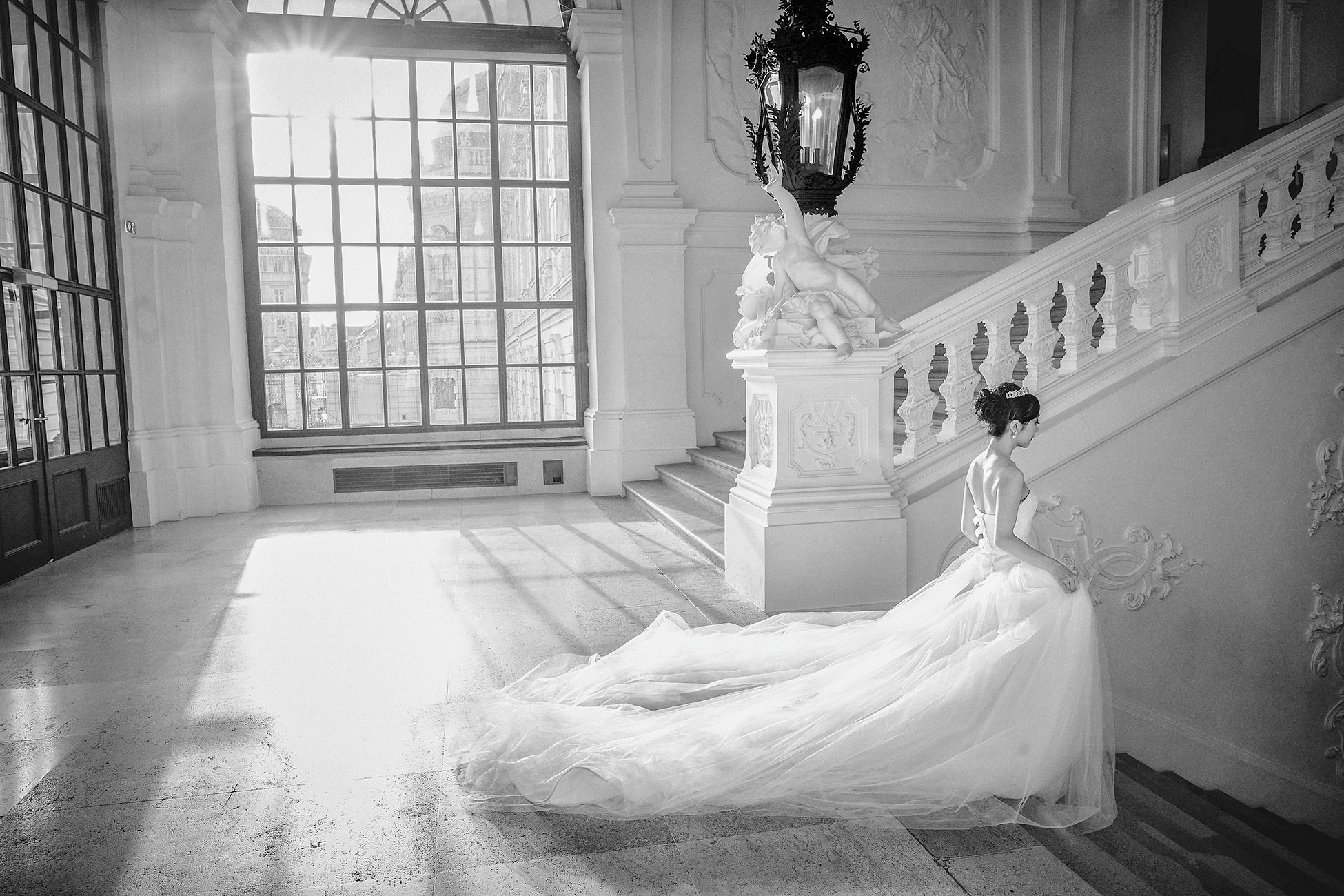 The bride with a flowing dress walks down the stairs of the famed Belvedere Palace, Vienna.