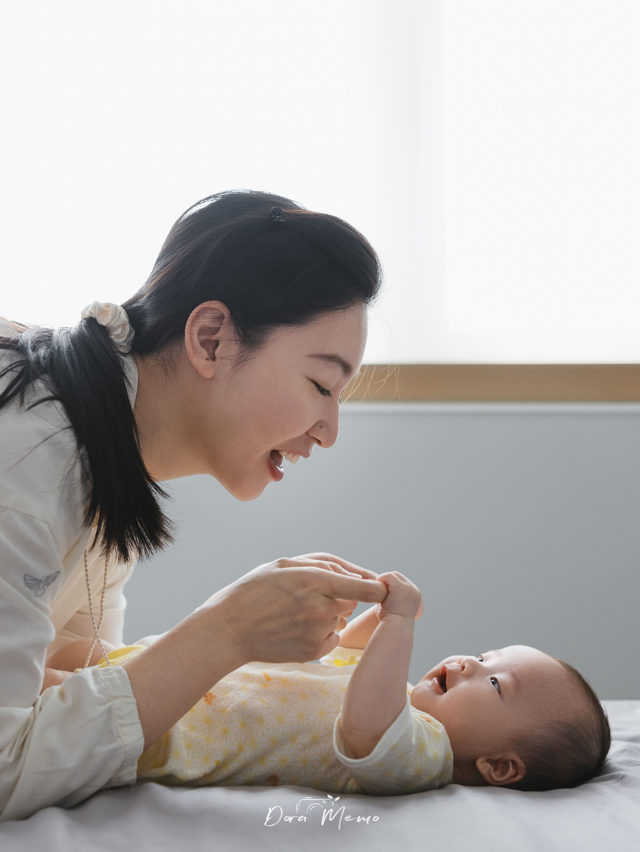 In a Shanghai family photoshoot, the mother is making her 100-day-old baby laugh.